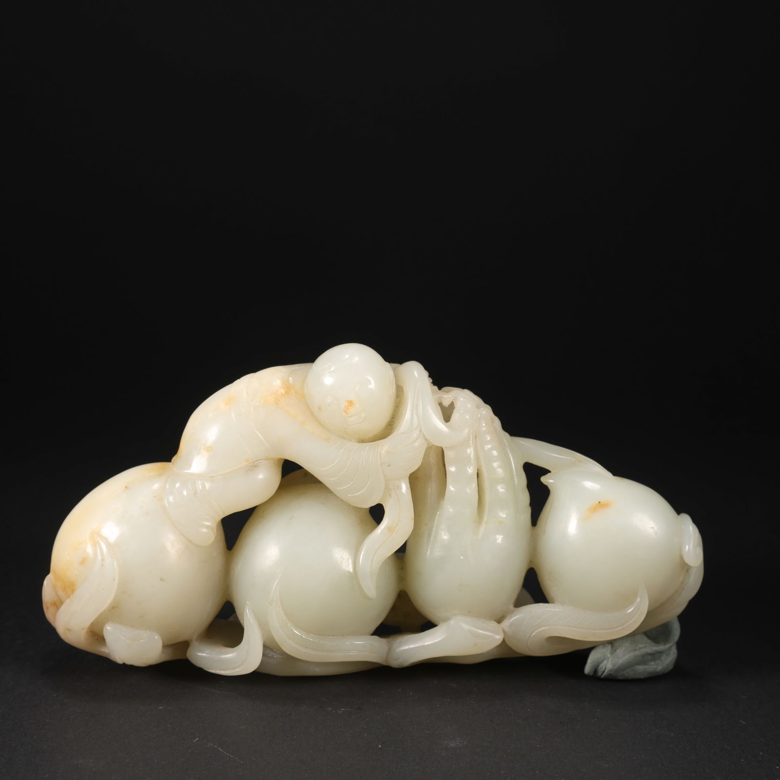 A HETIAN JADE FIGURINE OF CHILD OFFERING AUSPICIOUS SYMBOLS, SYMBOLIZING MANY CHILDREN AND BLESSINGS: Hetian Jade Figurine of Child Offering Auspicious Symbols, Symbolizing Many Children and Blessings