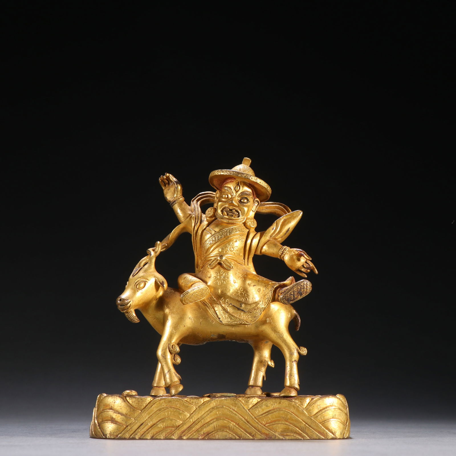 A GILDED BRONZE DHARMA PROTECTOR RIDING A SHEEP: Gilded Bronze Dharma Protector Riding a Sheep