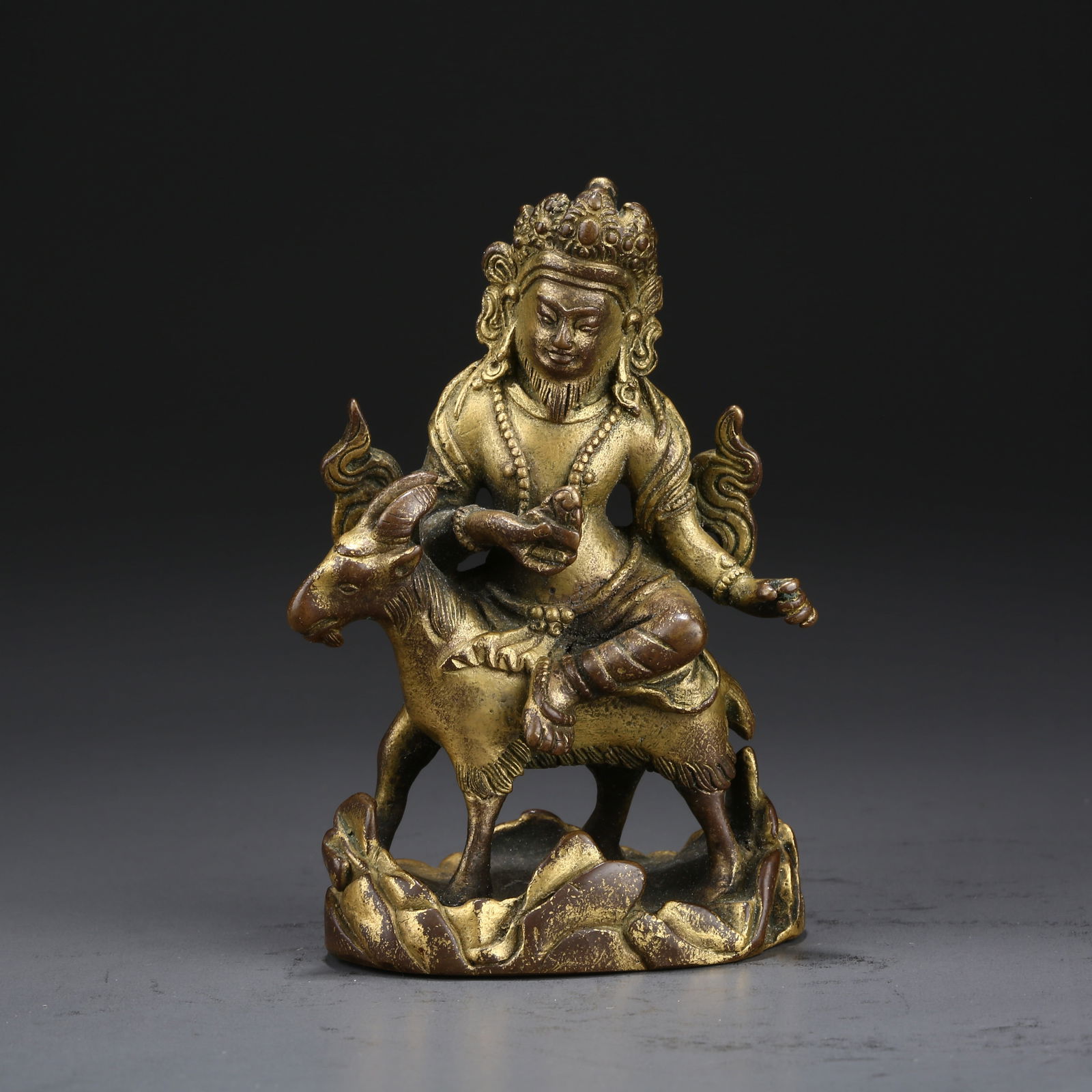 A GILT BRONZE PORTABLE STATUE OF THE DHARMA PROTECTOR RIDING A GOAT (1 of 9)