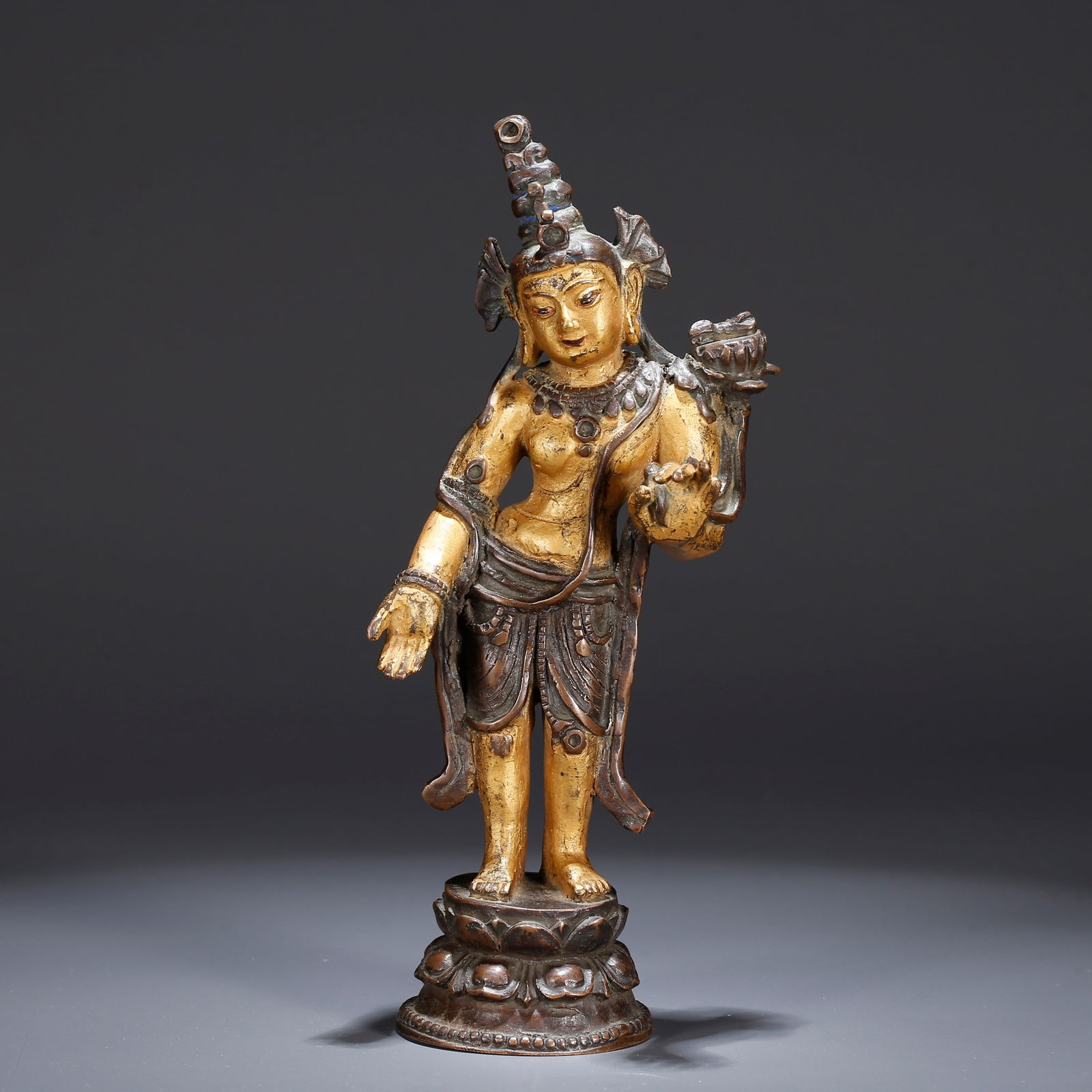 A GILT BRONZE STANDING AVALOKITESHVARA HOLDING A LOTUS (1 of 9)