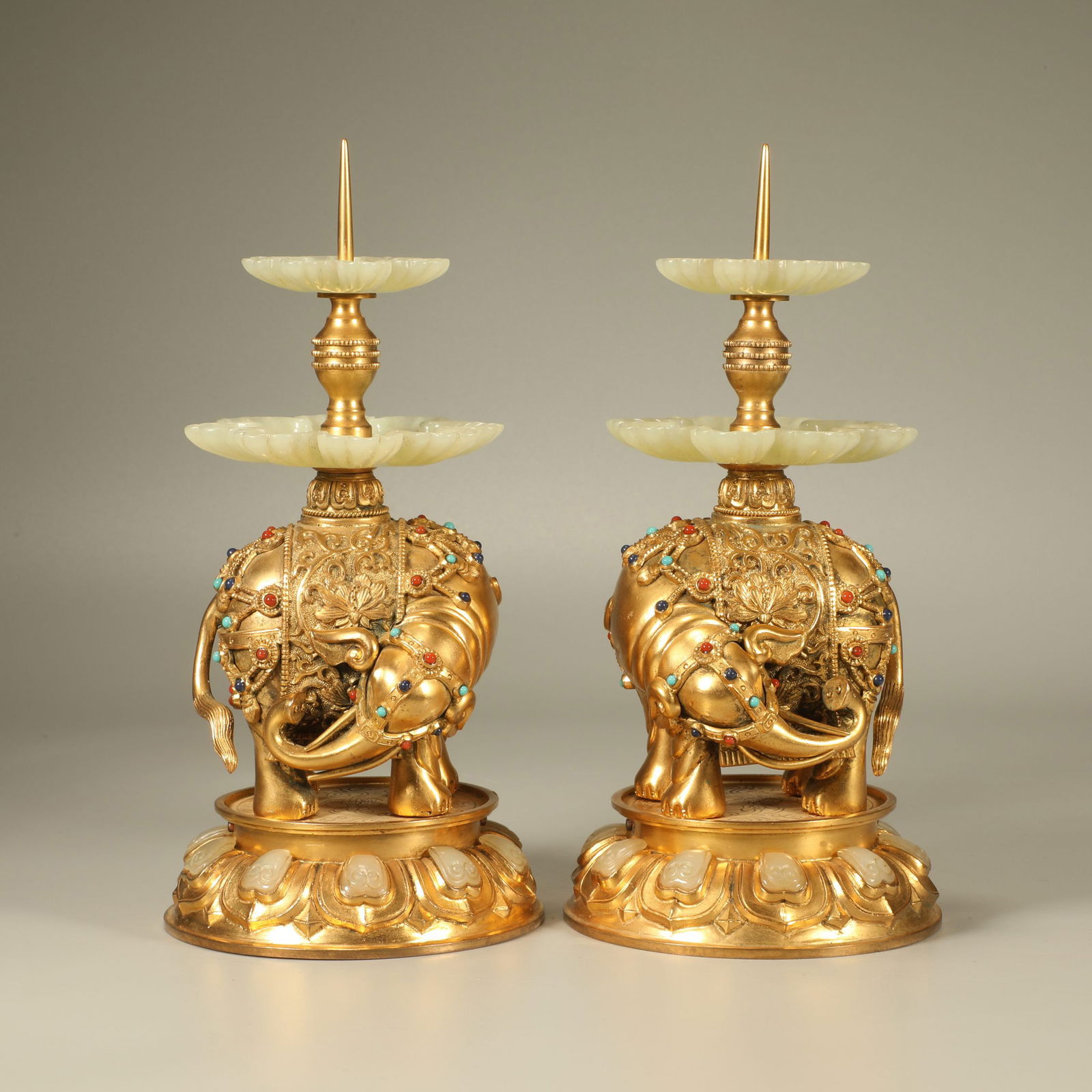 A GILT-BRONZE CANDLESTICKS INLAID WITH JADE AND GEMSTONES, DECORATED WITH THE AUSPICIOUS MOTIF: Gilt-bronze candlesticks inlaid with jade and gemstones, decorated with the auspicious motif "Peace Brought by the Elephant," pair