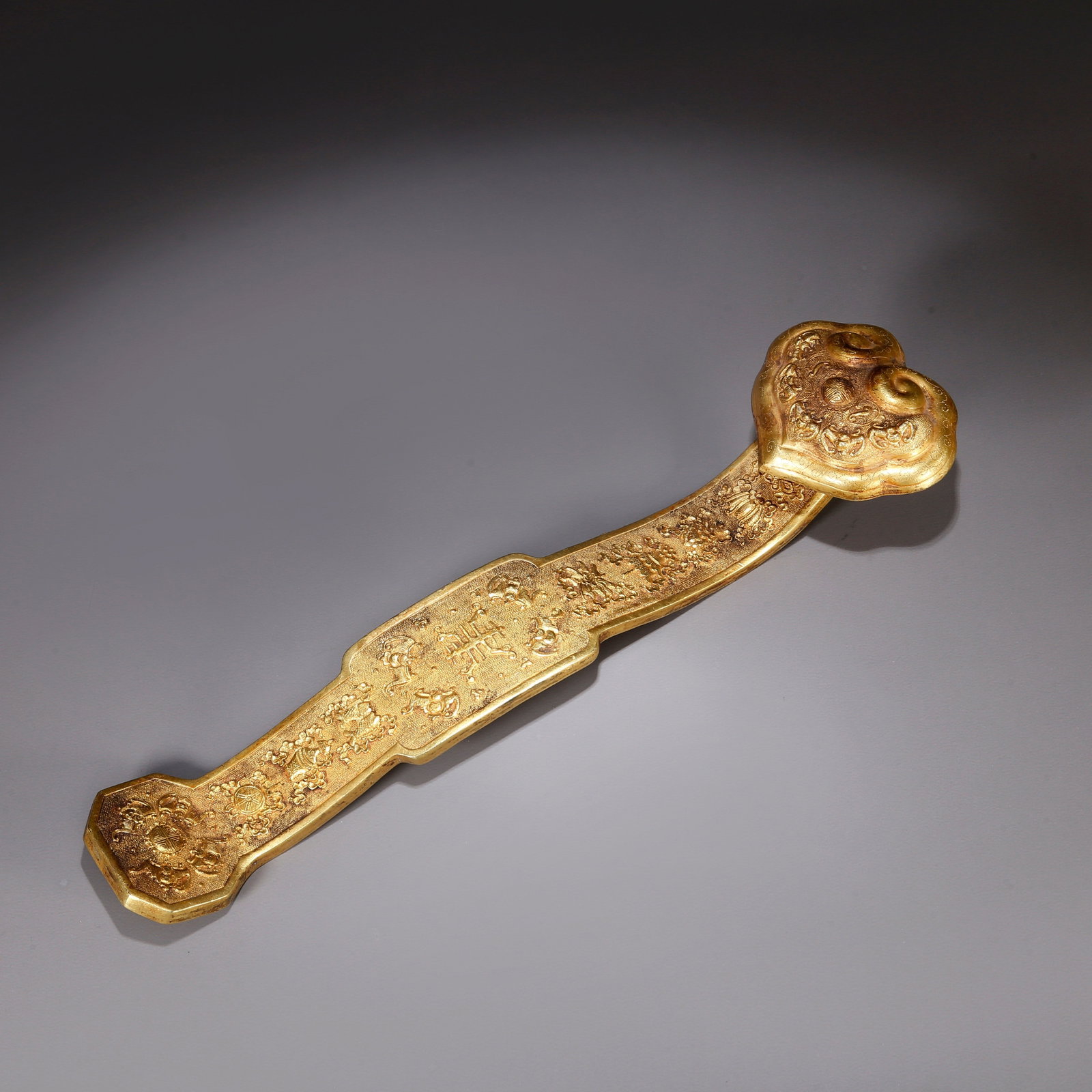 A GILT BRONZE RUYI SCEPTER WITH "FIVE BLESSINGS CARRY LONGEVITY" MOTIF: Gilt bronze ruyi scepter with "Five Blessings Carry Longevity" motif