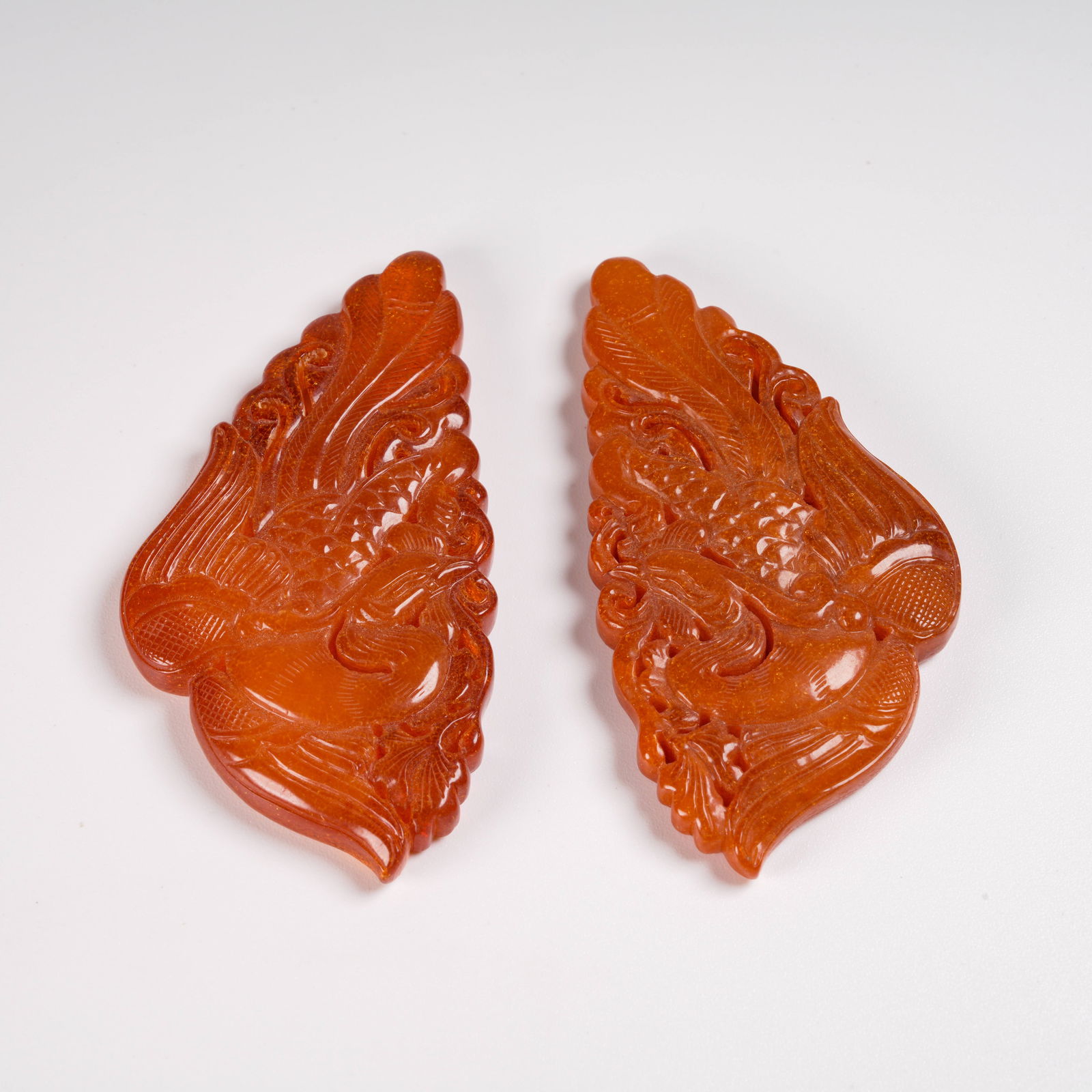 A SET OF HONEY-AMBER PENDANTS WITH PHOENIX MOTIFS: Set of honey-amber pendants with phoenix motifs
