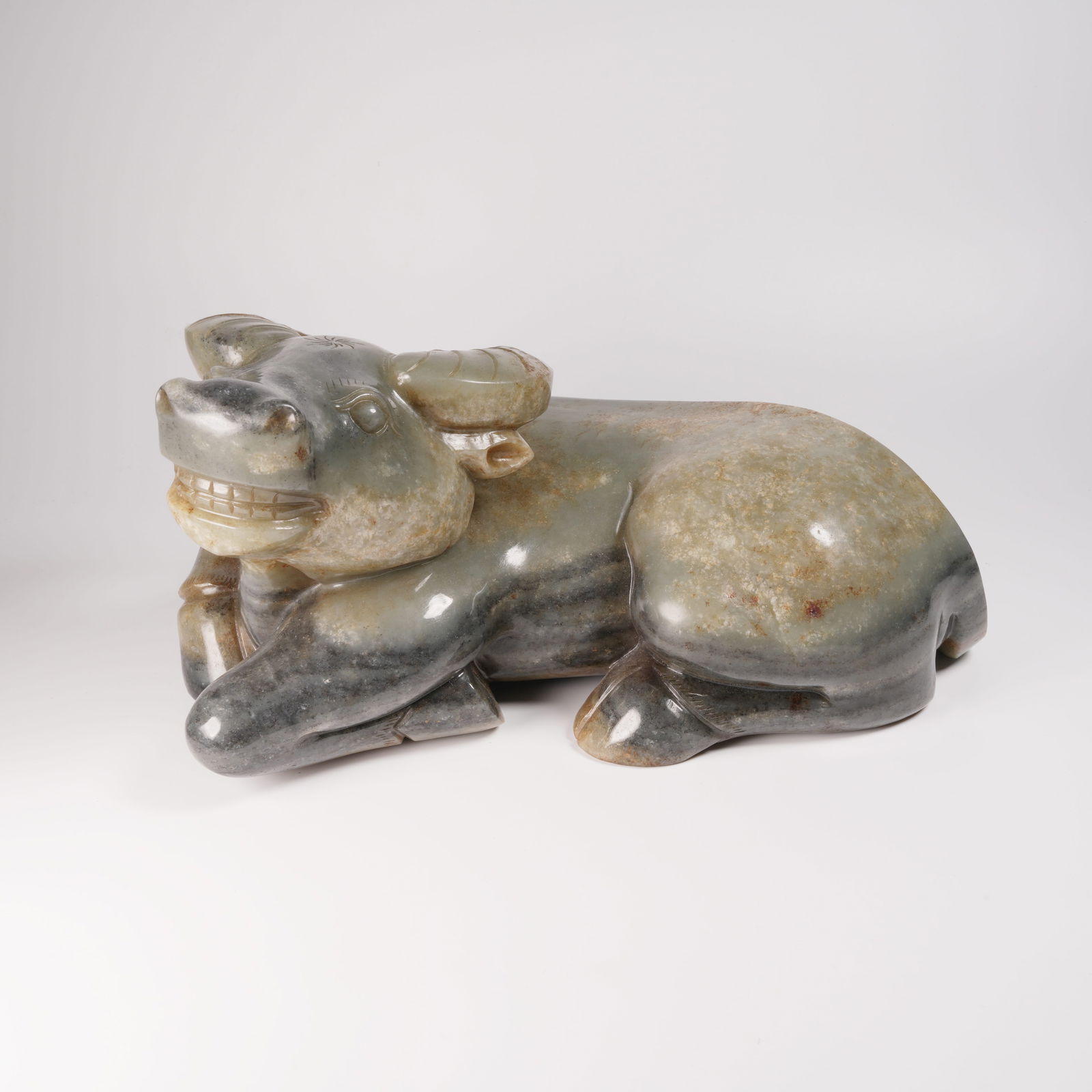 A HETIAN BLUE-AND-WHITE JADE SEED MATERIAL RECUMBENT OX FIGURE: Hetian blue-and-white jade seed material recumbent ox figure