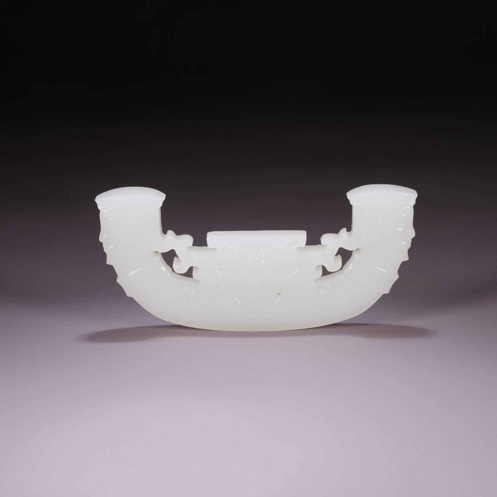 A HETIAN JADE ARC-SHAPED PENDANT WITH DEITY FACE MOTIF: Hetian Jade Arc-Shaped Pendant with Deity Face Motif