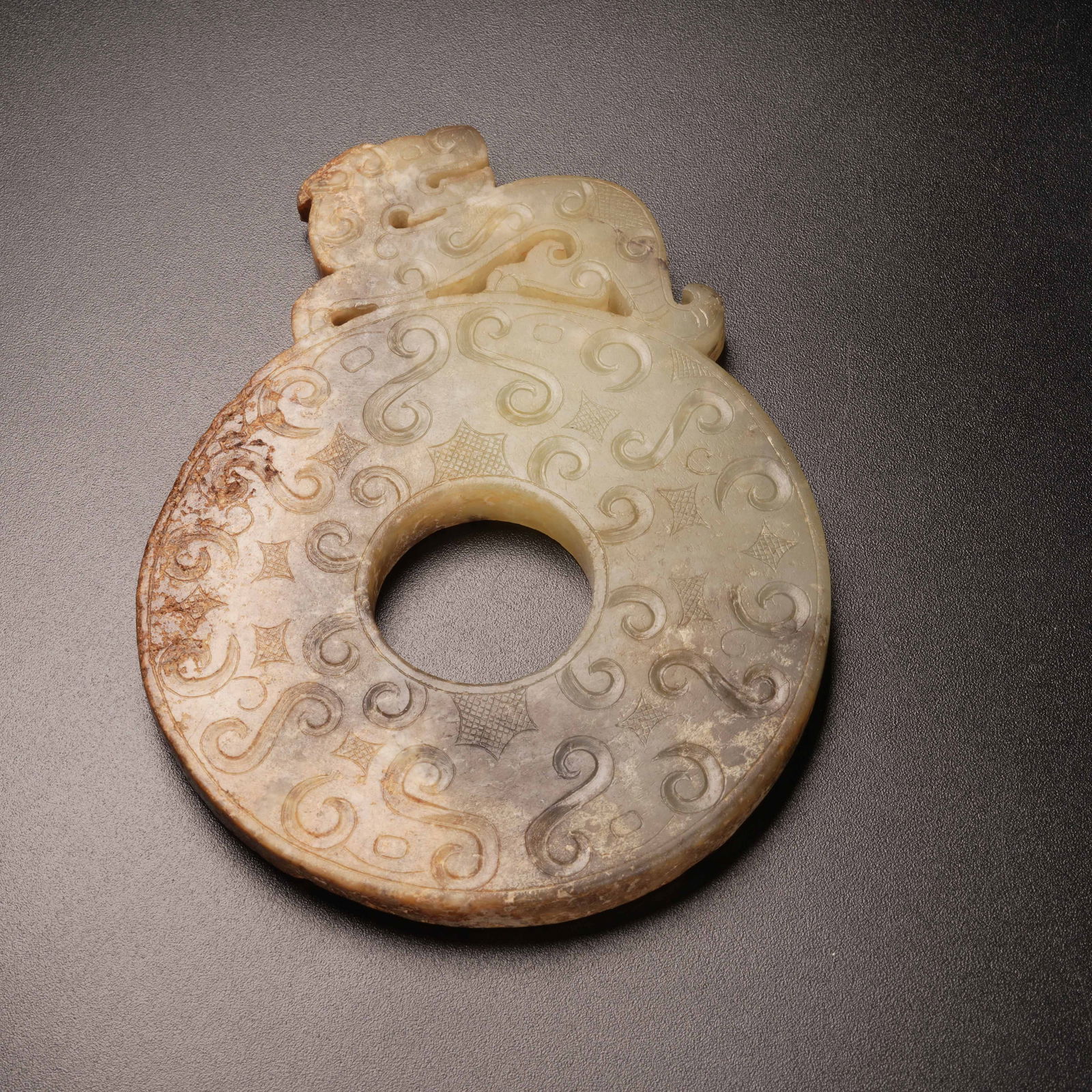 A ANCIENT JADE BEAST-PATTERNED BI DISC WITH RAISED RIM: Ancient jade beast-patterned bi disc with raised rim