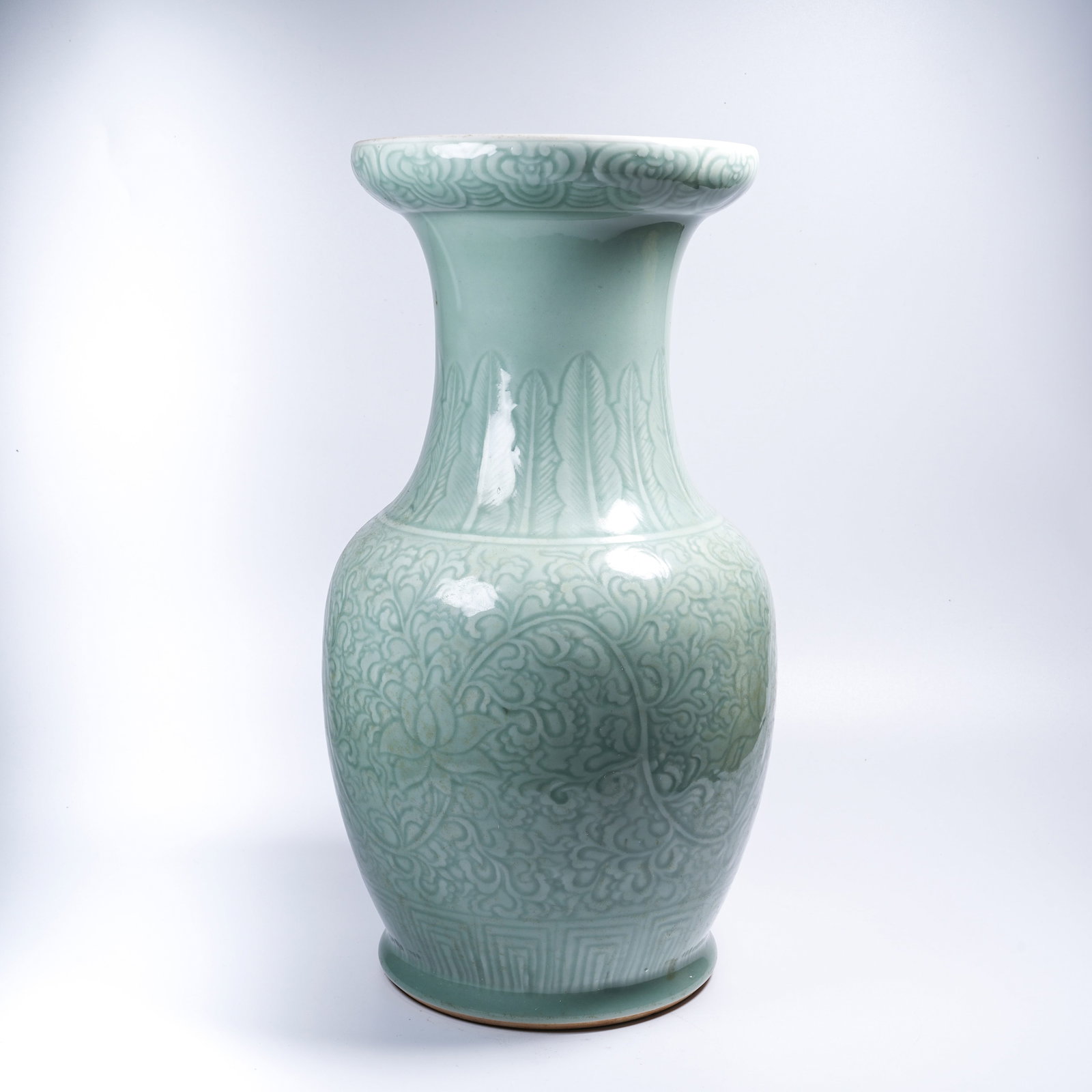 A CELADON-GLAZED ZUN WITH SCROLLING FLORAL DESIGN AND FLARED MOUTH: Celadon-glazed zun with scrolling floral design and flared mouth