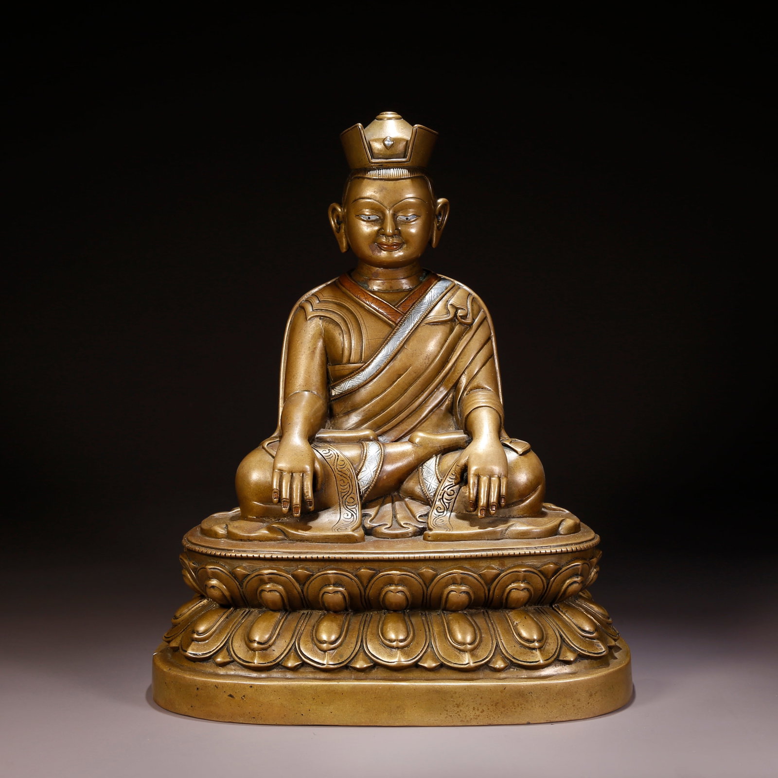 A SILVER- AND RED-BRONZE INLAID LAMA FIGURE: Silver- and Red-Bronze Inlaid Lama Figure