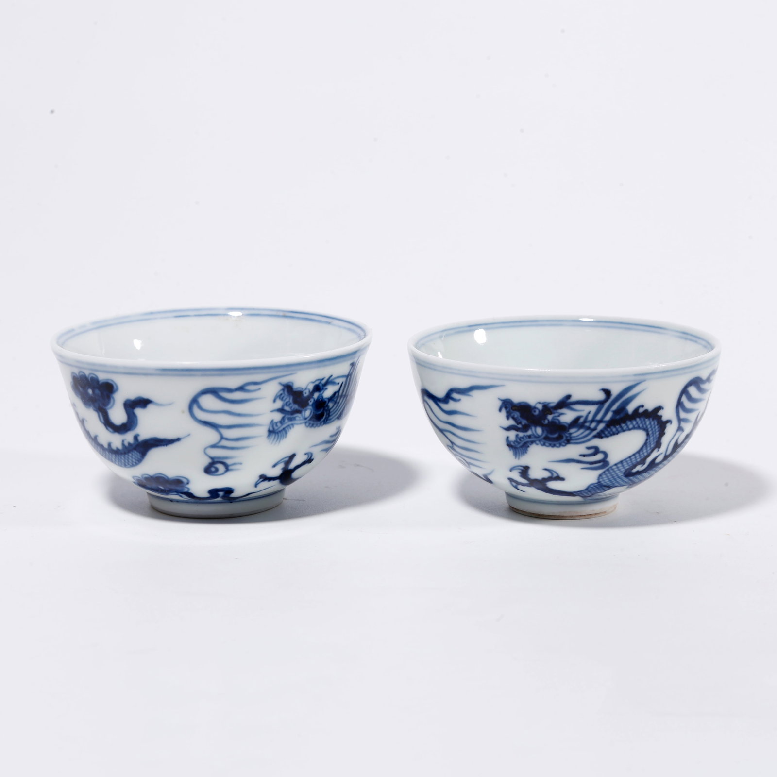 A PAIR OF BLUE AND WHITE CUPS WITH CLOUD AND DRAGON PATTERN: Pair of Blue and White Cups with Cloud and Dragon Pattern