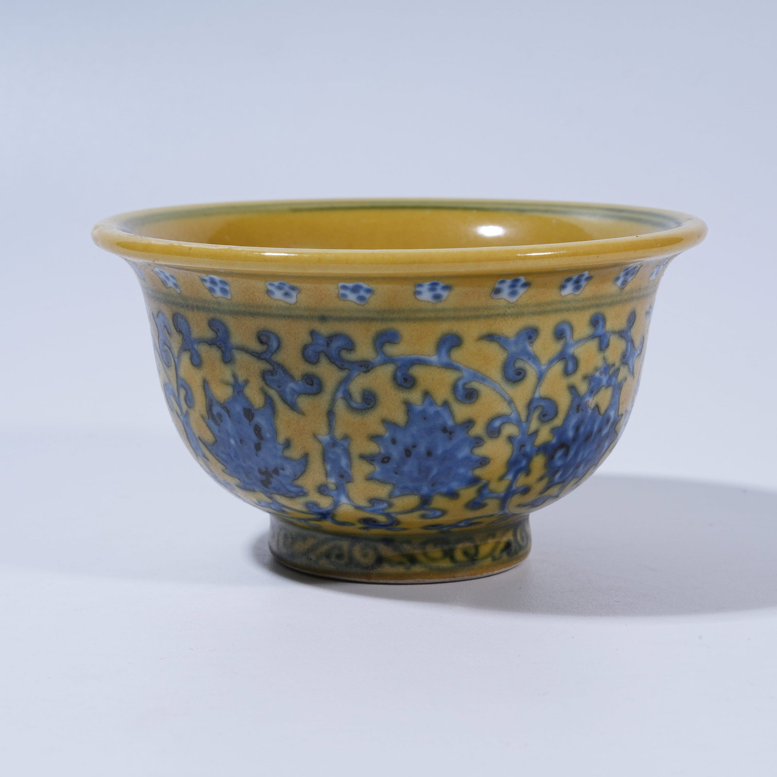 A YELLOW-GROUND BLUE-AND-WHITE CUP WITH INTERTWINING FLORAL SCROLLS: Yellow-Ground Blue-and-White Cup with Intertwining Floral Scrolls