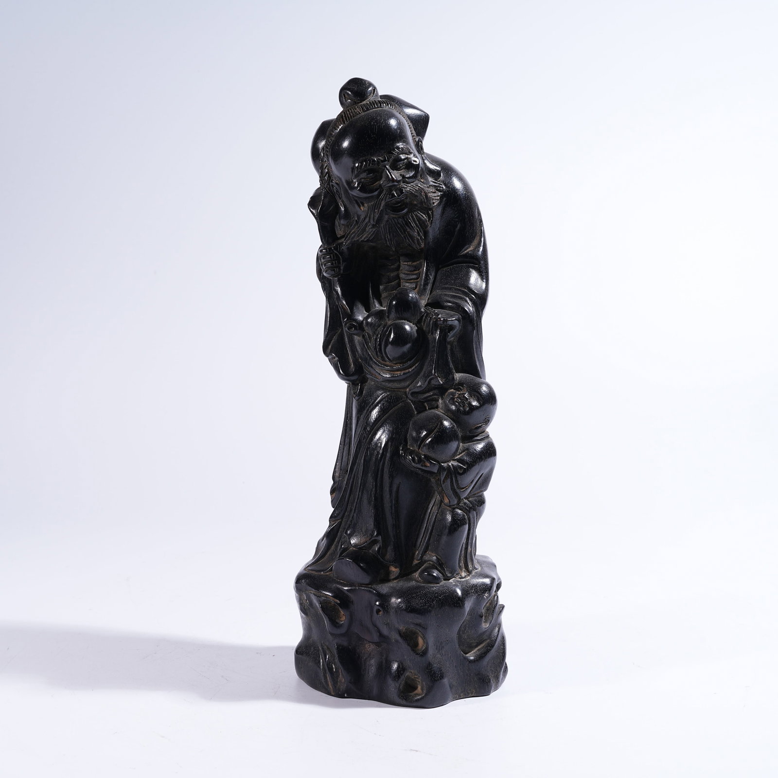 A ZITAN FIGURINE OF A BOY OFFERING LONGEVITY: Zitan Figurine of a Boy Offering Longevity