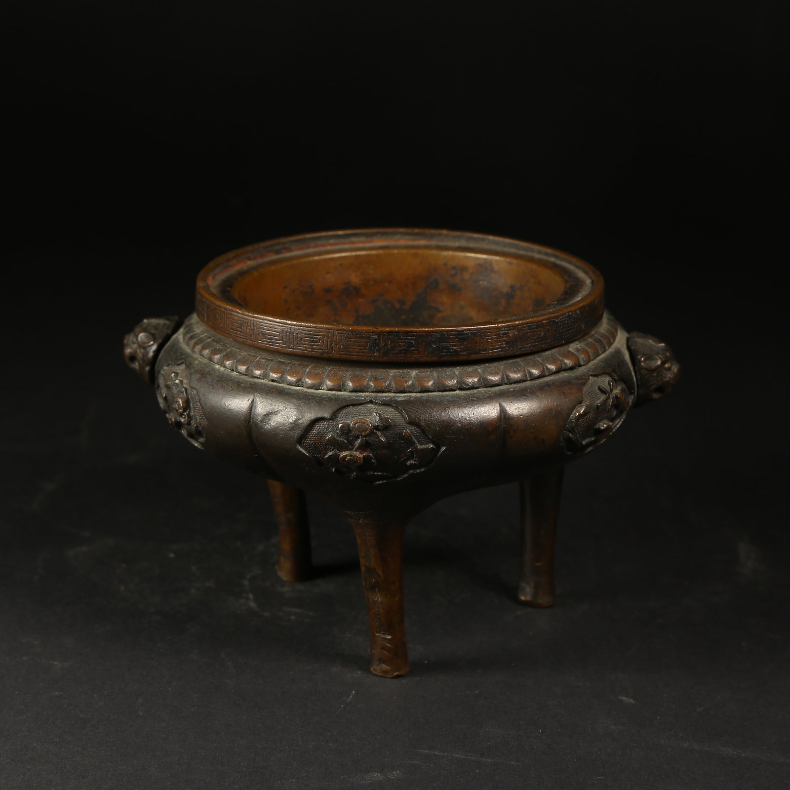 A BRONZE THREE-LEGGED CENSER WITH FLORAL PATTERN AND BEAST-HEAD HANDLES: Bronze Three-Legged Censer with Floral Pattern and Beast-Head Handles