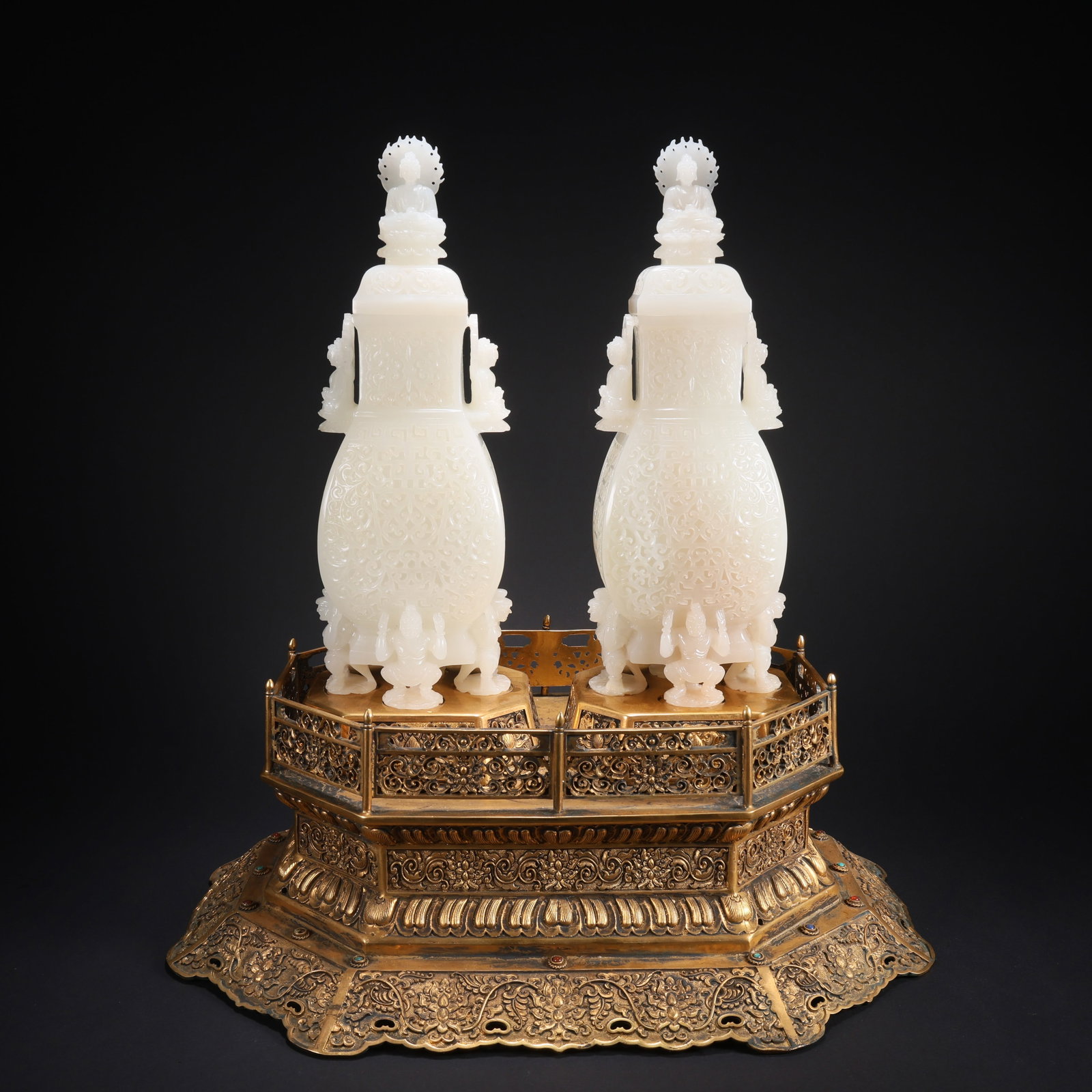 A HETIAN JADE GILDED BRONZE INLAID GEM BASE WITH FLORAL PATTERN SEVEN-BUDDHA COVERED BOTTLES, PAIR: Hetian Jade Gilded Bronze Inlaid Gem Base with Floral Pattern Seven-Buddha Covered Bottles, Pair