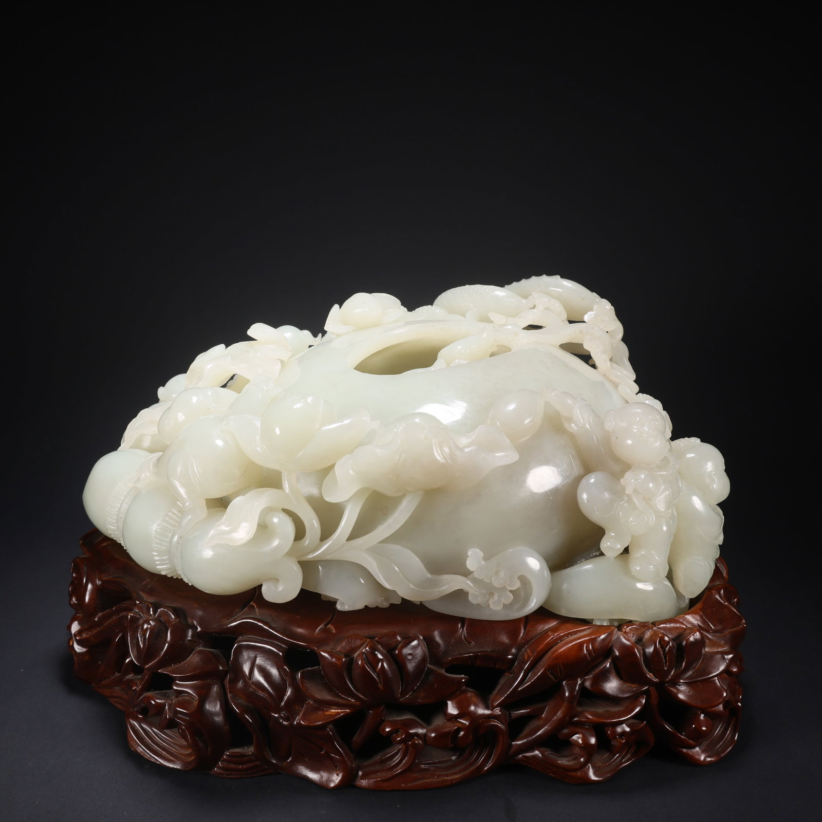 A HETIAN JADE WOODEN-BASE CHILDREN PLAYING WITH FISH AND LOTUS-ROOT BRUSH WASHER: Hetian Jade Wooden-Base Children Playing with Fish and Lotus-Root Brush Washer