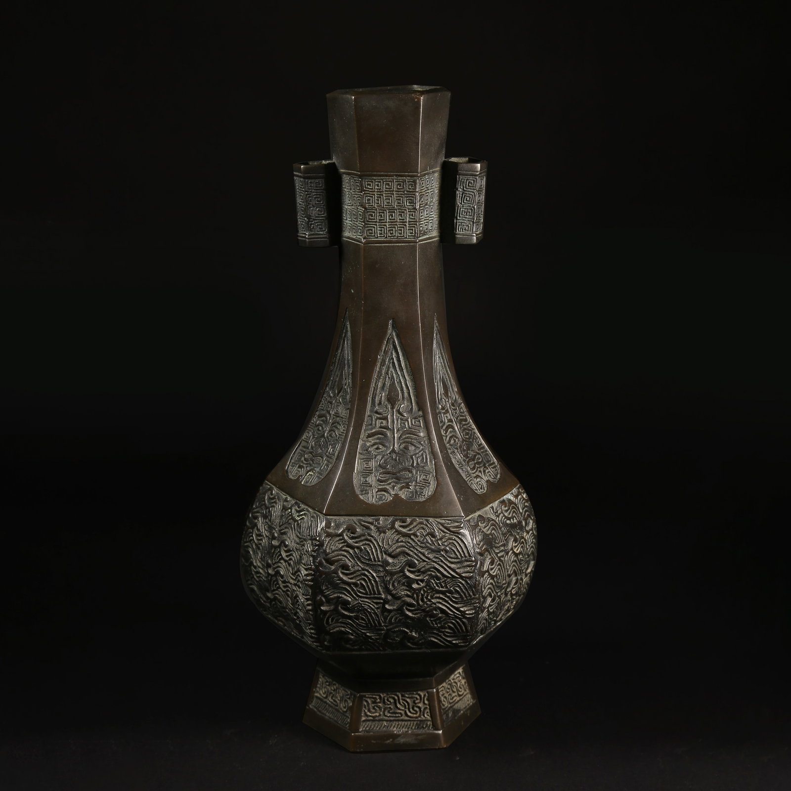 A BRONZE HEXAGONAL BOTTLE WITH SEA-WAVE PATTERN AND LOOP HANDLES: Bronze Hexagonal Bottle with Sea-Wave Pattern and Loop Handles