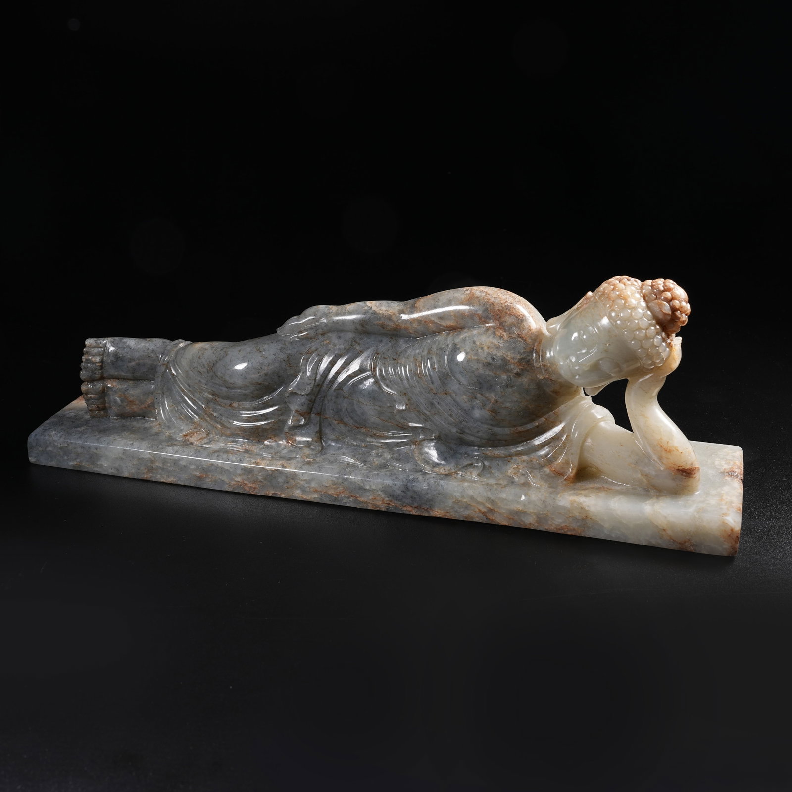 A HETIAN INK-SPLASHED SEED JADE RECUMBENT BUDDHA ORNAMENT (1 of 9)