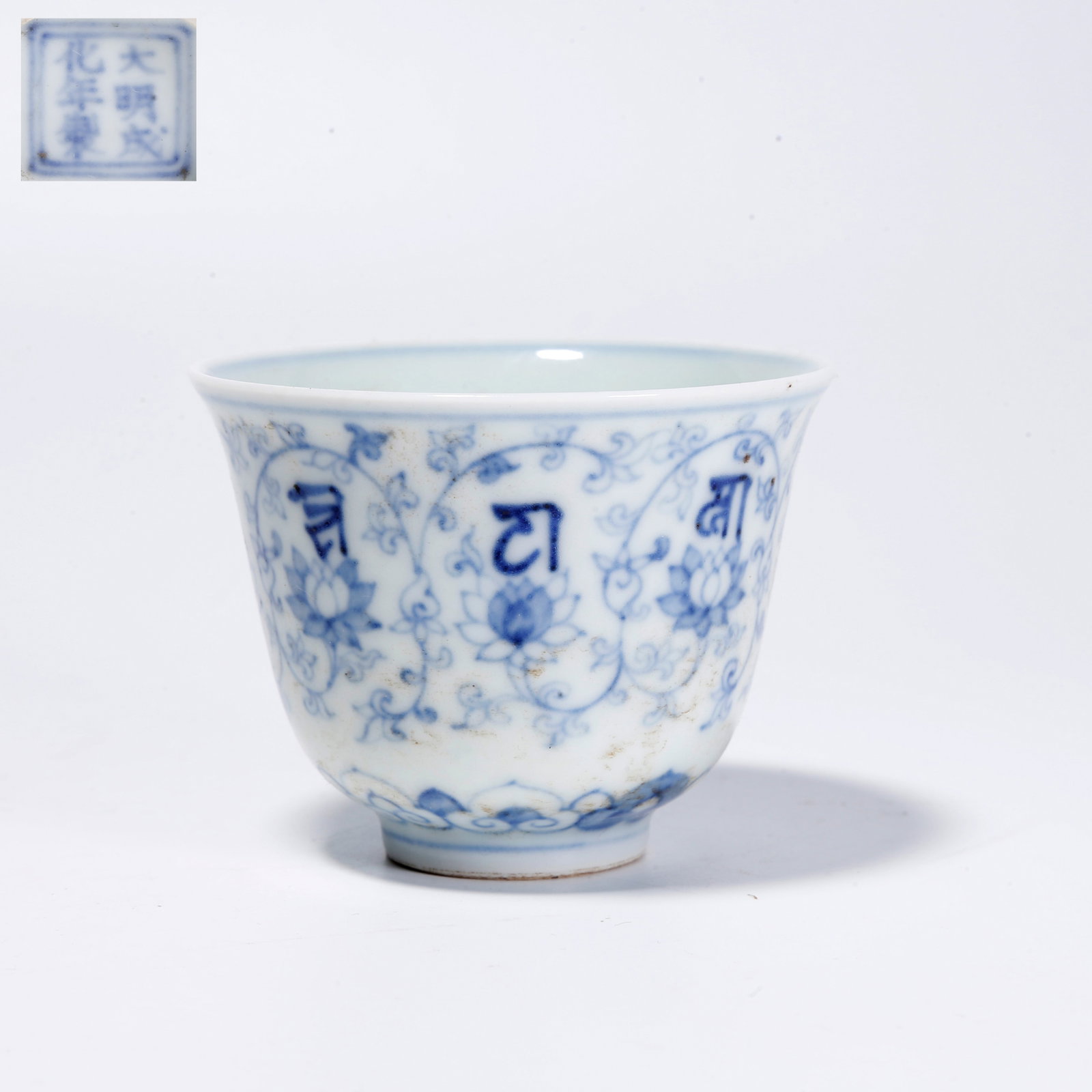 A BLUE-AND-WHITE CUP WITH FLOWER AND SANSKRIT PATTERN: Blue-and-White Cup with Flower and Sanskrit Pattern