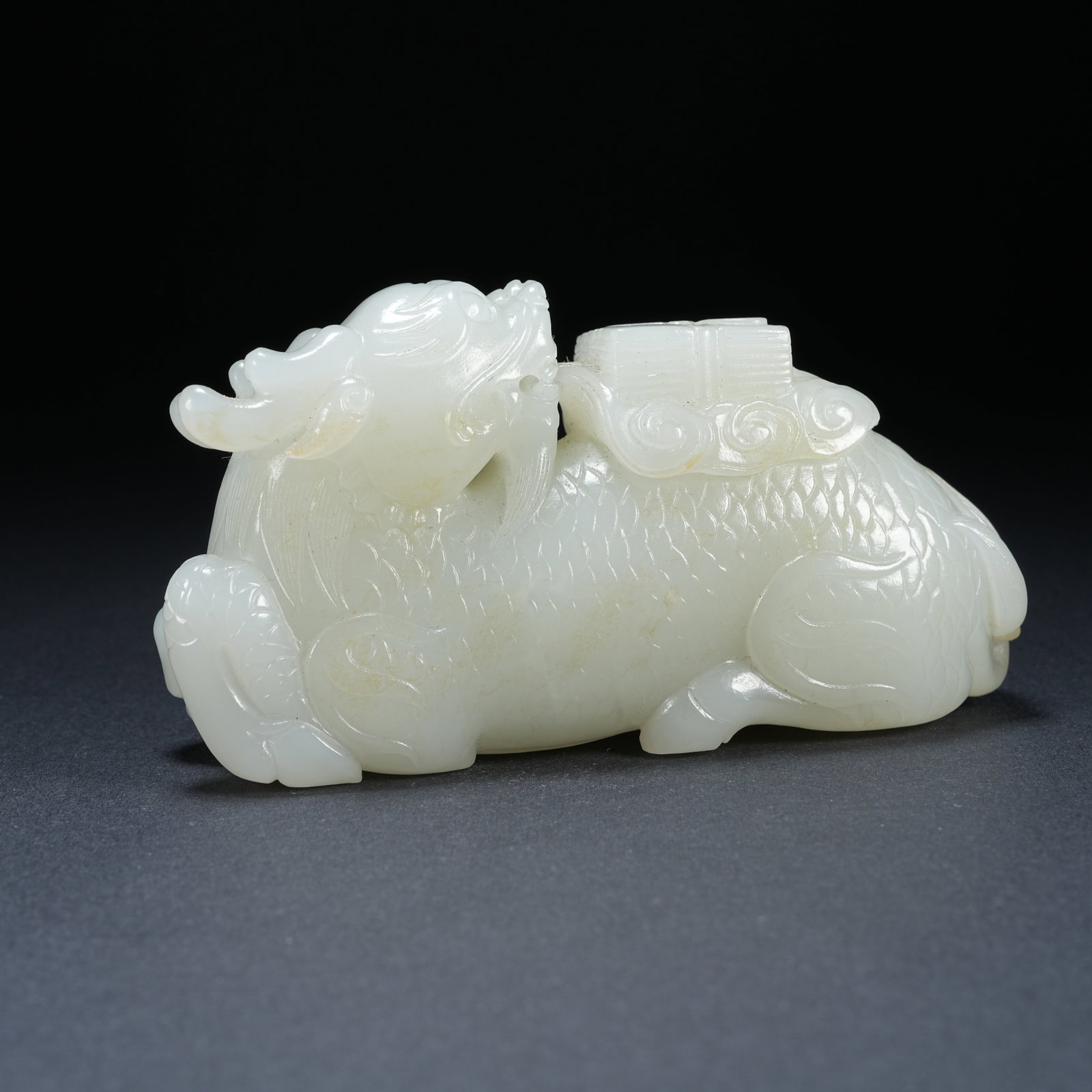 A HETIAN JADE QILIN CARRYING SCROLL ORNAMENT: Hetian Jade Qilin Carrying Scroll Ornament