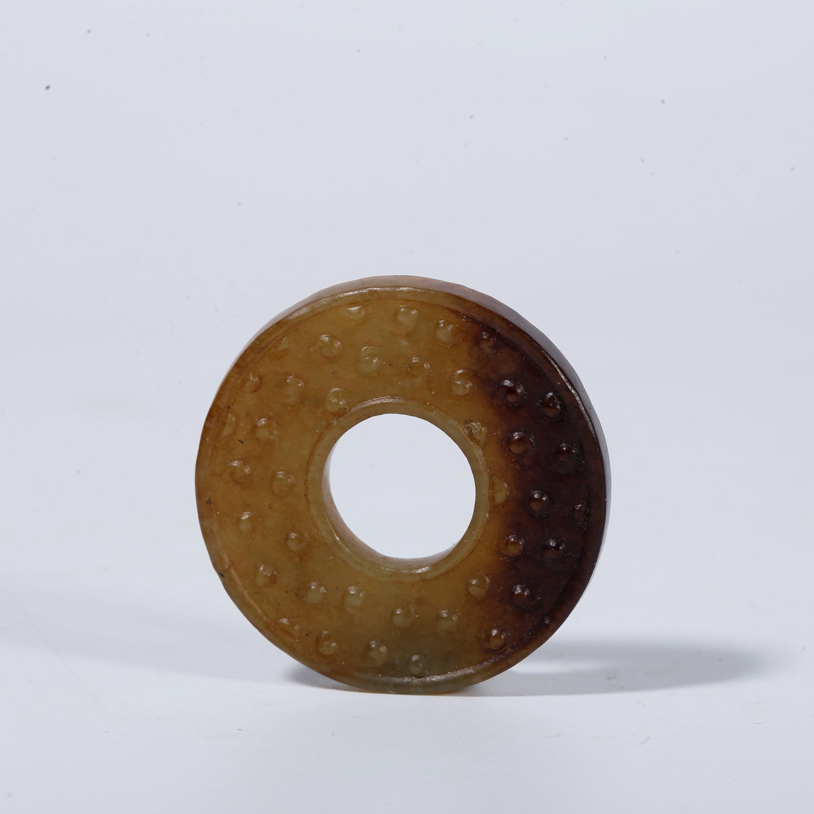 A SMALL ANCIENT JADE LOOPED BI DISC CARVED WITH NAIL PATTERN: Small Ancient Jade Looped Bi Disc Carved with Nail Pattern
