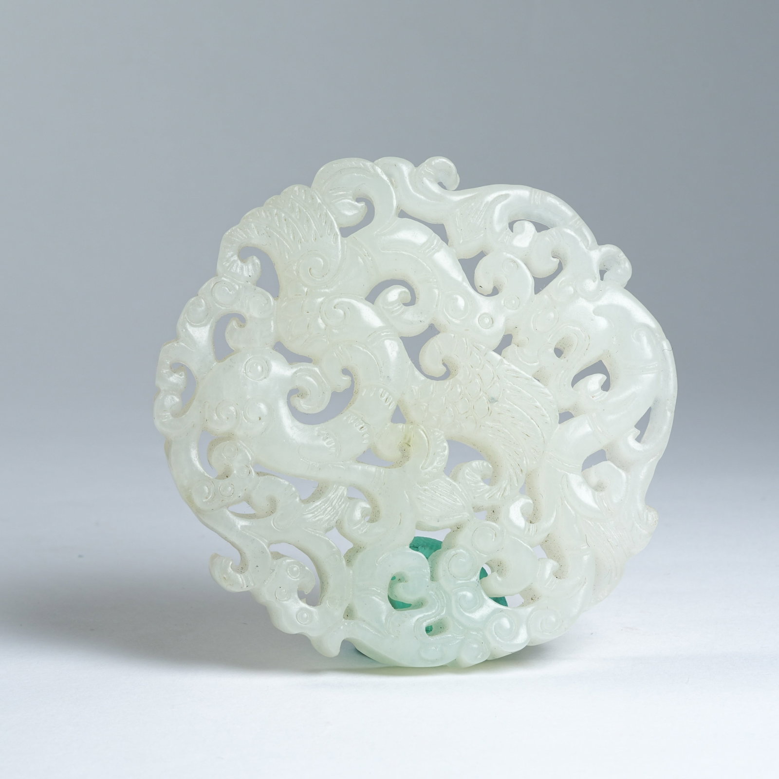 A HETIAN JADE PENDANT WITH PHOENIX AMIDST FLORAL PATTERNS: Hetian Jade Pendant with Phoenix Amidst Floral Patterns