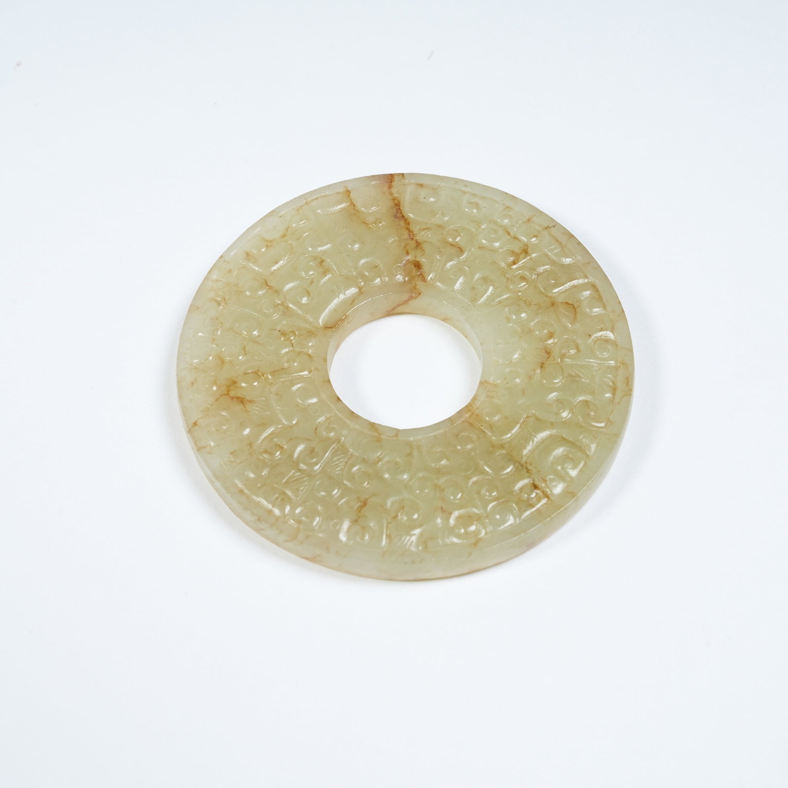 A ANCIENT JADE BI WITH INTERLOCKING CLOUD PATTERNS: Ancient Jade Bi with Interlocking Cloud Patterns