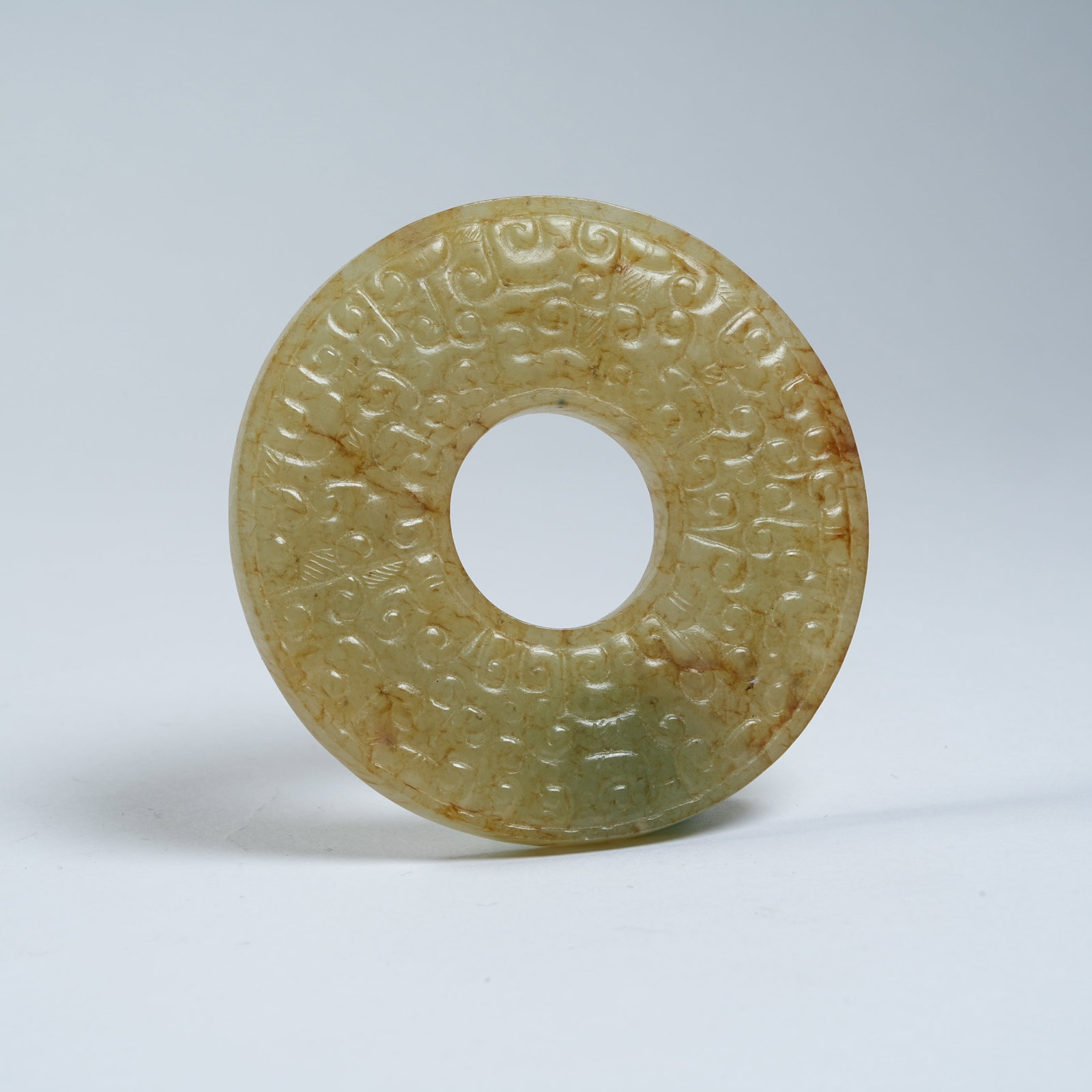 A ANCIENT JADE BI WITH INTERLOCKING CLOUD PATTERNS: Ancient Jade Bi with Interlocking Cloud Patterns