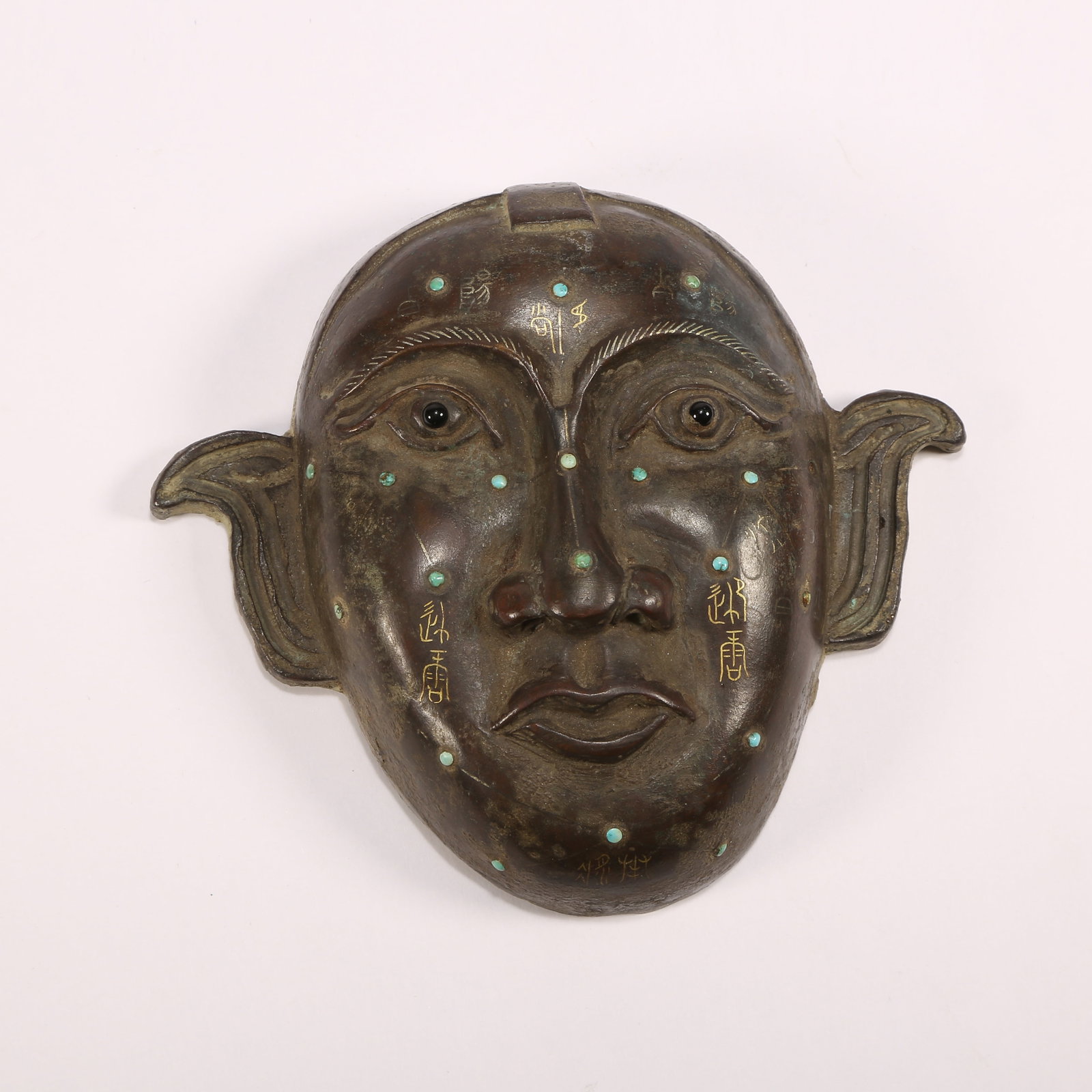 A BRONZE MASK WITH GILT-INLAID GOLD, SILVER, AND GEMSTONES: Bronze mask with gilt-inlaid gold, silver, and gemstones