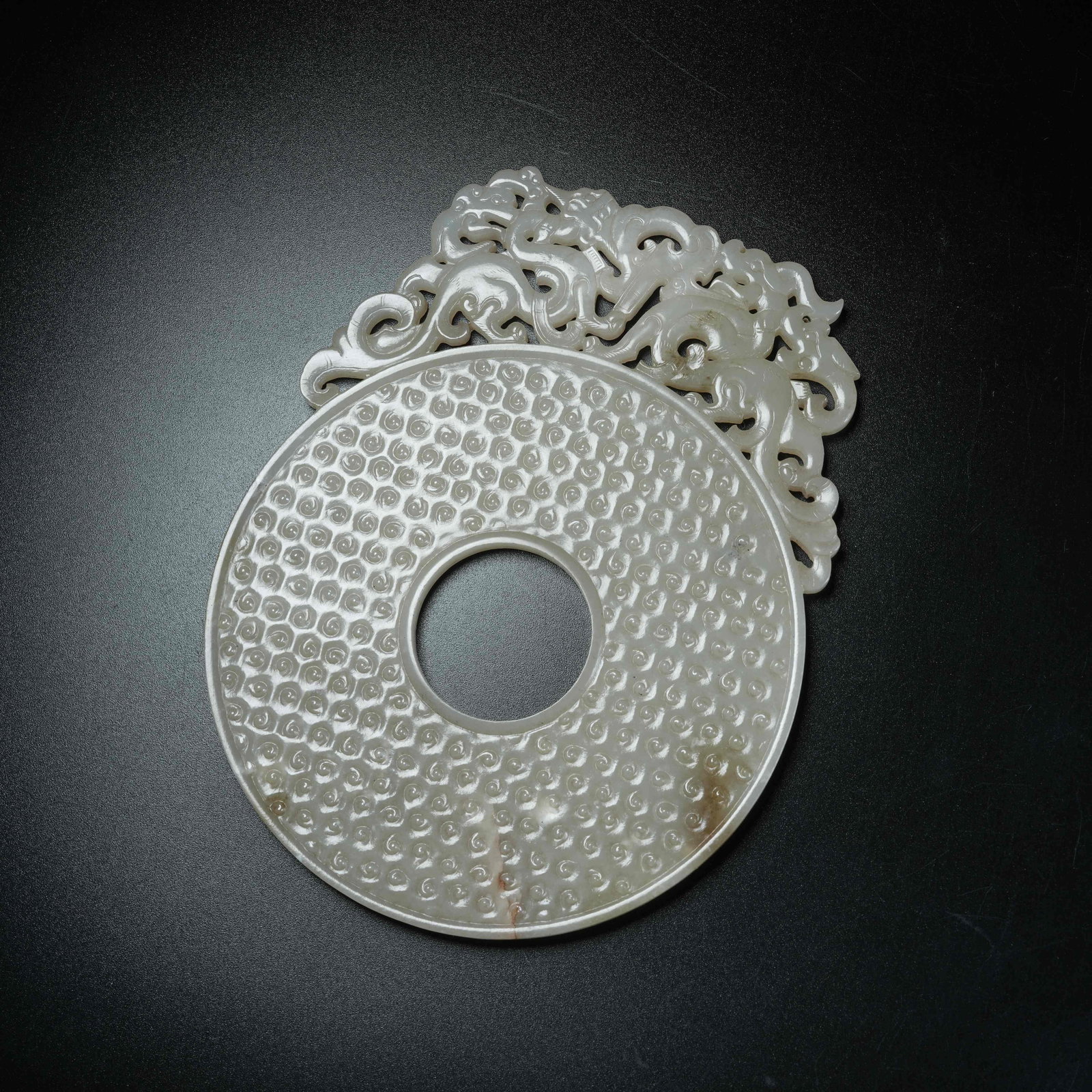 A ANCIENT JADE OPENWORK BI DISC CARVED WITH DRAGON PATTERNS EXTENDING BEYOND RIM: Ancient Jade Openwork Bi Disc Carved with Dragon Patterns Extending Beyond Rim