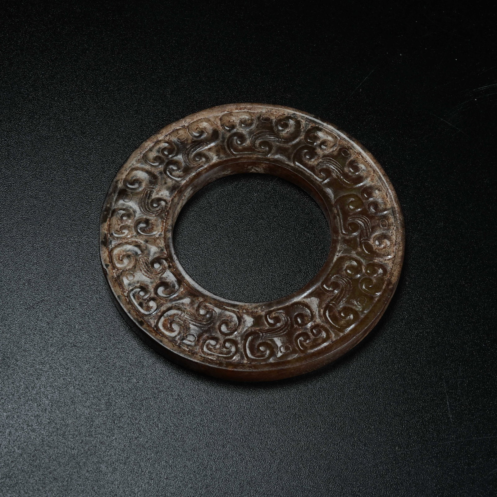 A ANCIENT JADE BI DISC CARVED WITH HOOKED CLOUD PATTERNS: Ancient Jade Bi Disc Carved with Hooked Cloud Patterns