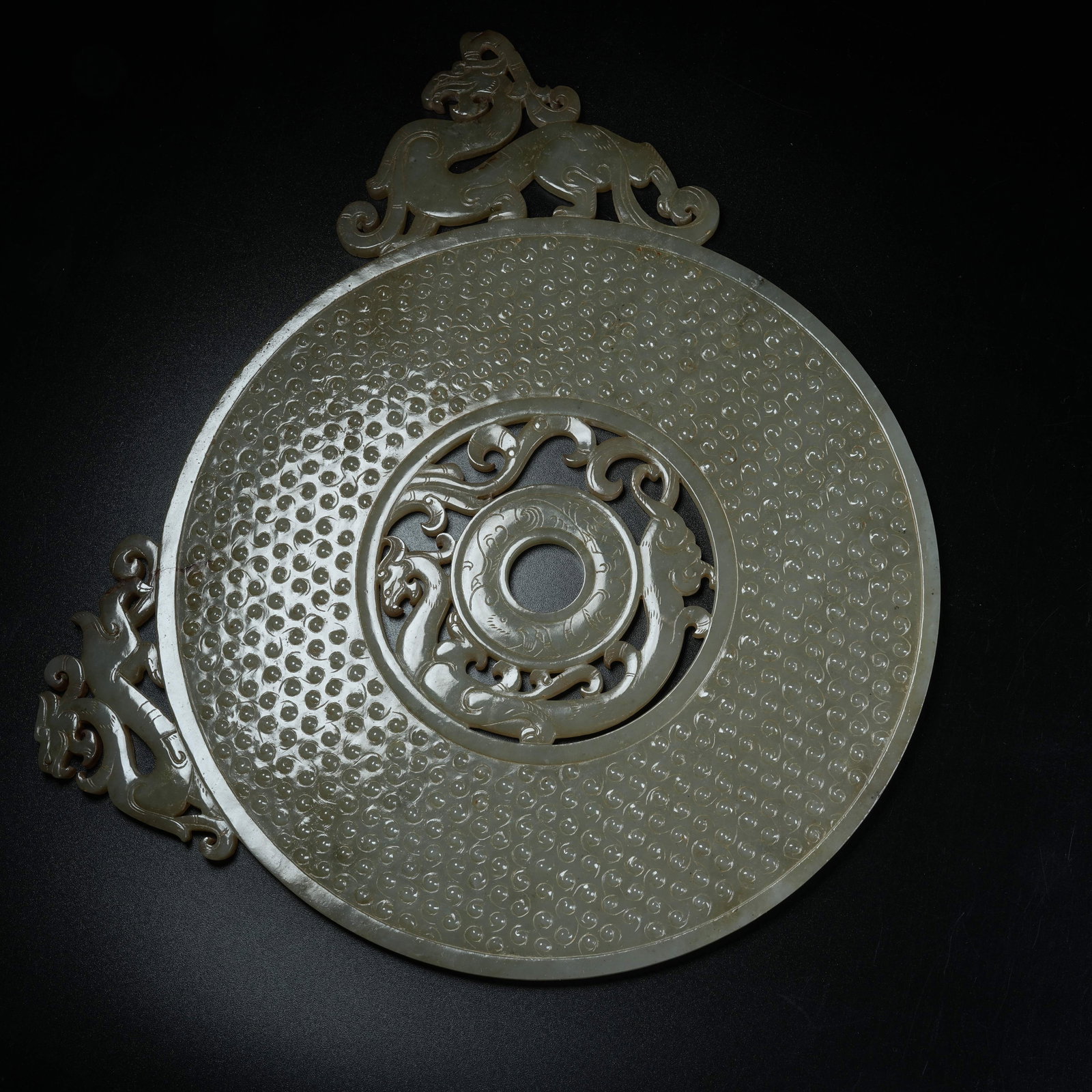 A ANCIENT JADE OPENWORK BI DISC CARVED WITH CHI DRAGON PATTERNS EXTENDING BEYOND RIM: Ancient Jade Openwork Bi Disc Carved with Chi Dragon Patterns Extending Beyond Rim