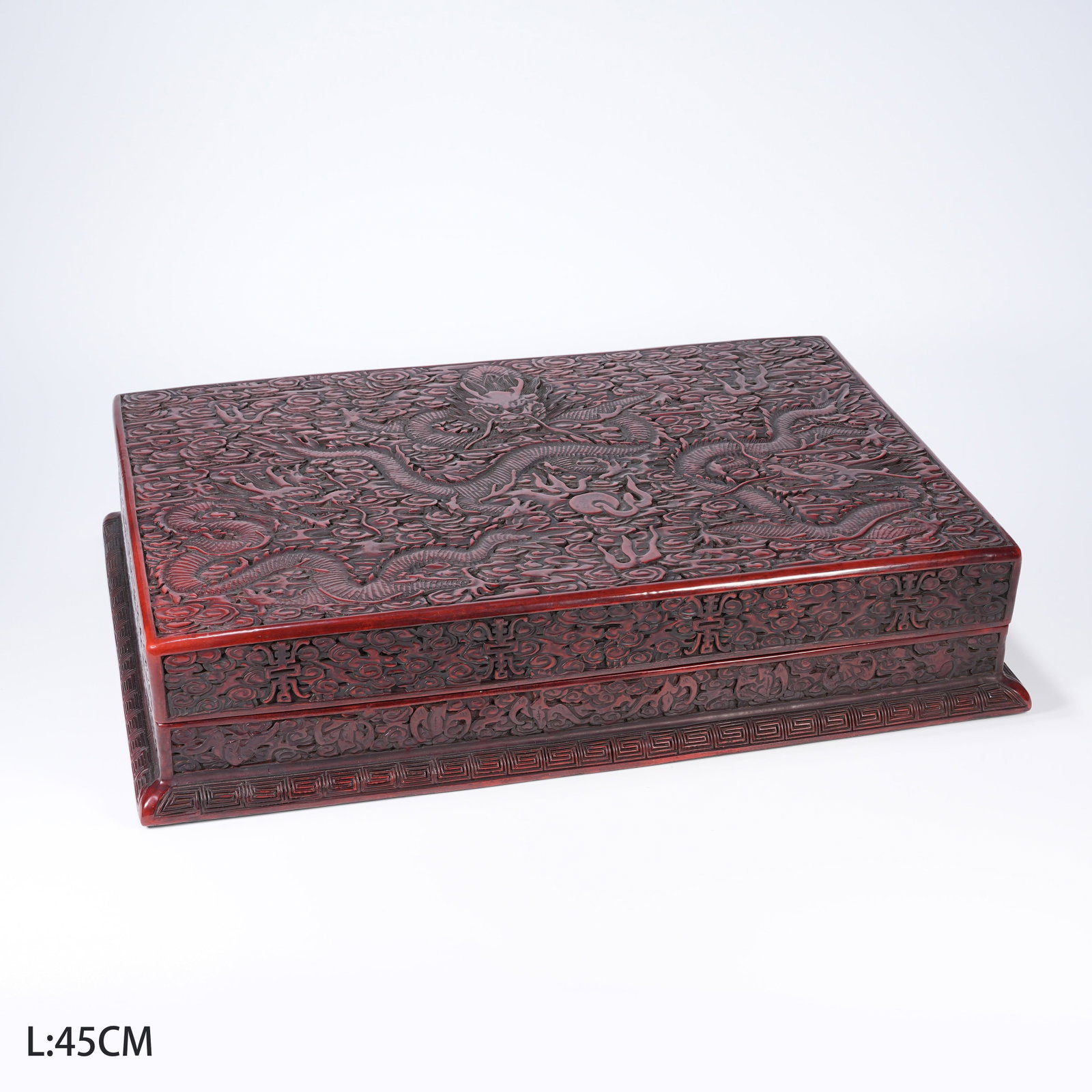 A CARVED RED LACQUER COVERED BOX WITH CLOUD-DRAGON PATTERNS: Carved red lacquer covered box with cloud-dragon patterns