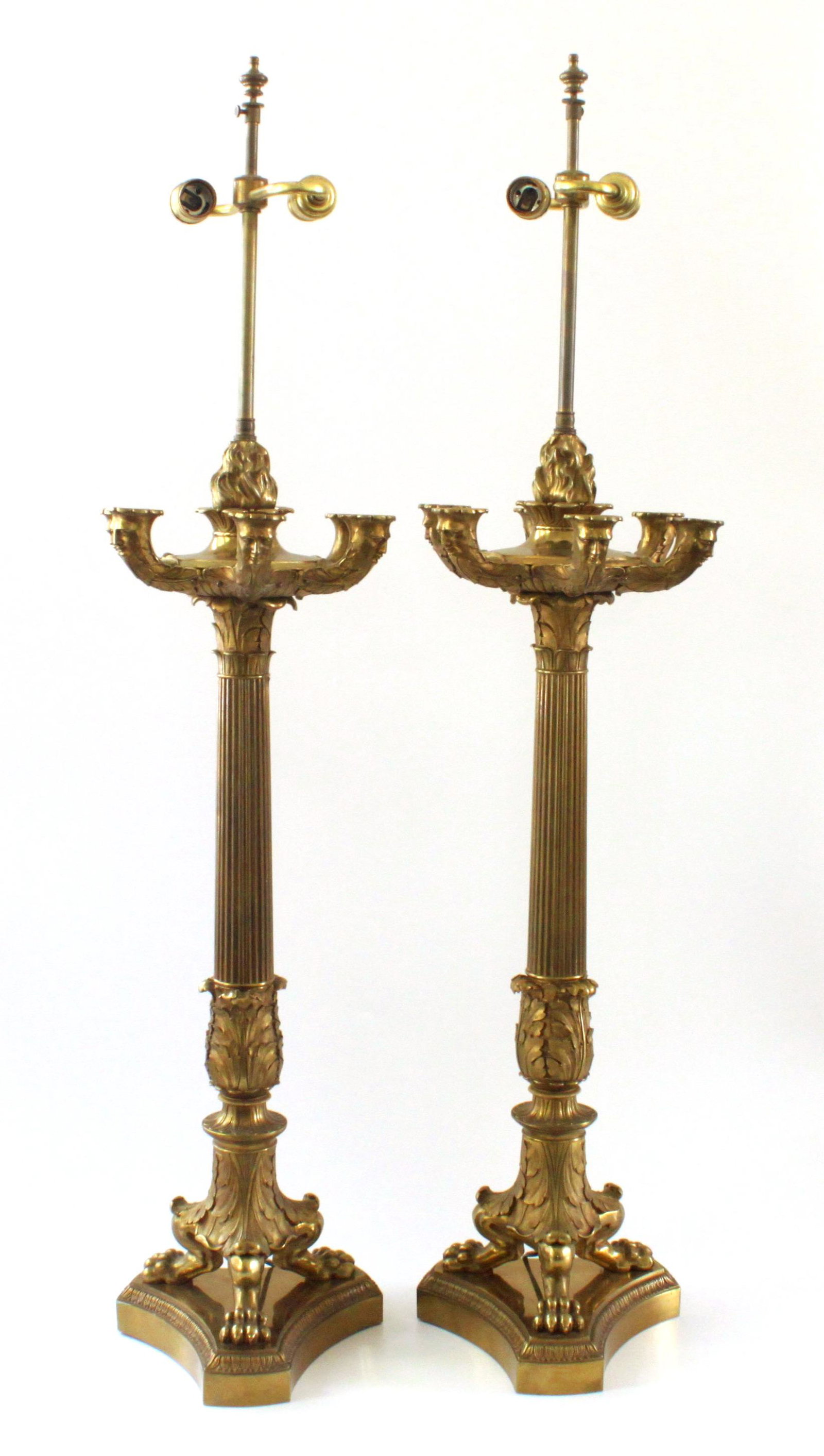 Gilt-bronze candelabra hardwired lamps c. 1900, a pair: A pair of gilt-bronze candelabra, converted to lamps, c. 1900. The design features four up-scrolled branches cast with masks centred on flambeaux above reeded baluster stems cast with acanthus leaves 