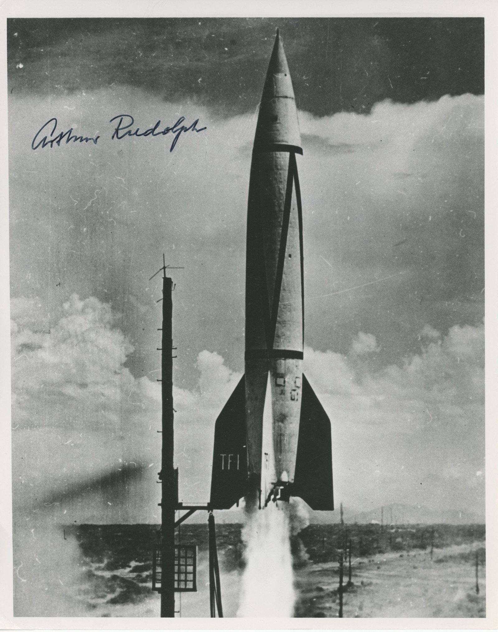 Arthur Rudolph – German V-2 Rocket Engineer & NASA Director – Autographed 8 x 10 Photo: Details: Arthur Rudolph autographed 8 x 10” glossy photograph depicting the dramatic liftoff of a V-2 rocket, identified as TF-1, rising from its launch platform amid plumes of smoke. Boldly sig