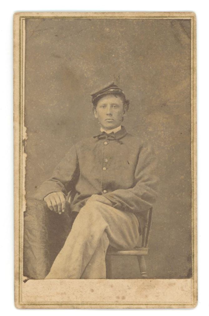 Civil War Soldier – Union Army Private – Carte de Visite (CDV) Photo – Seated Port: Details: Civil War soldier Carte de Visite (CDV) photograph depicting a young Union Army private seated in studio setting. He wears a regulation kepi and frock coat, posed with legs crossed and one ar