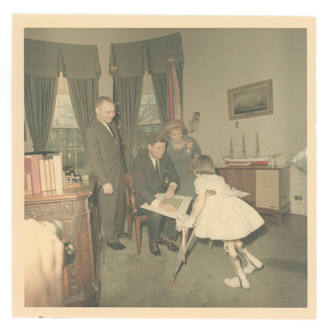 John F. Kennedy – Oval Office Photograph with Disabled Girl – Cecil Stoughton 5 x 5 Phot: Details: John F. Kennedy original first-generation 5 x 5” color photograph by White House photographer Cecil Stoughton, capturing a tender moment inside the Oval Office as President Kennedy bend