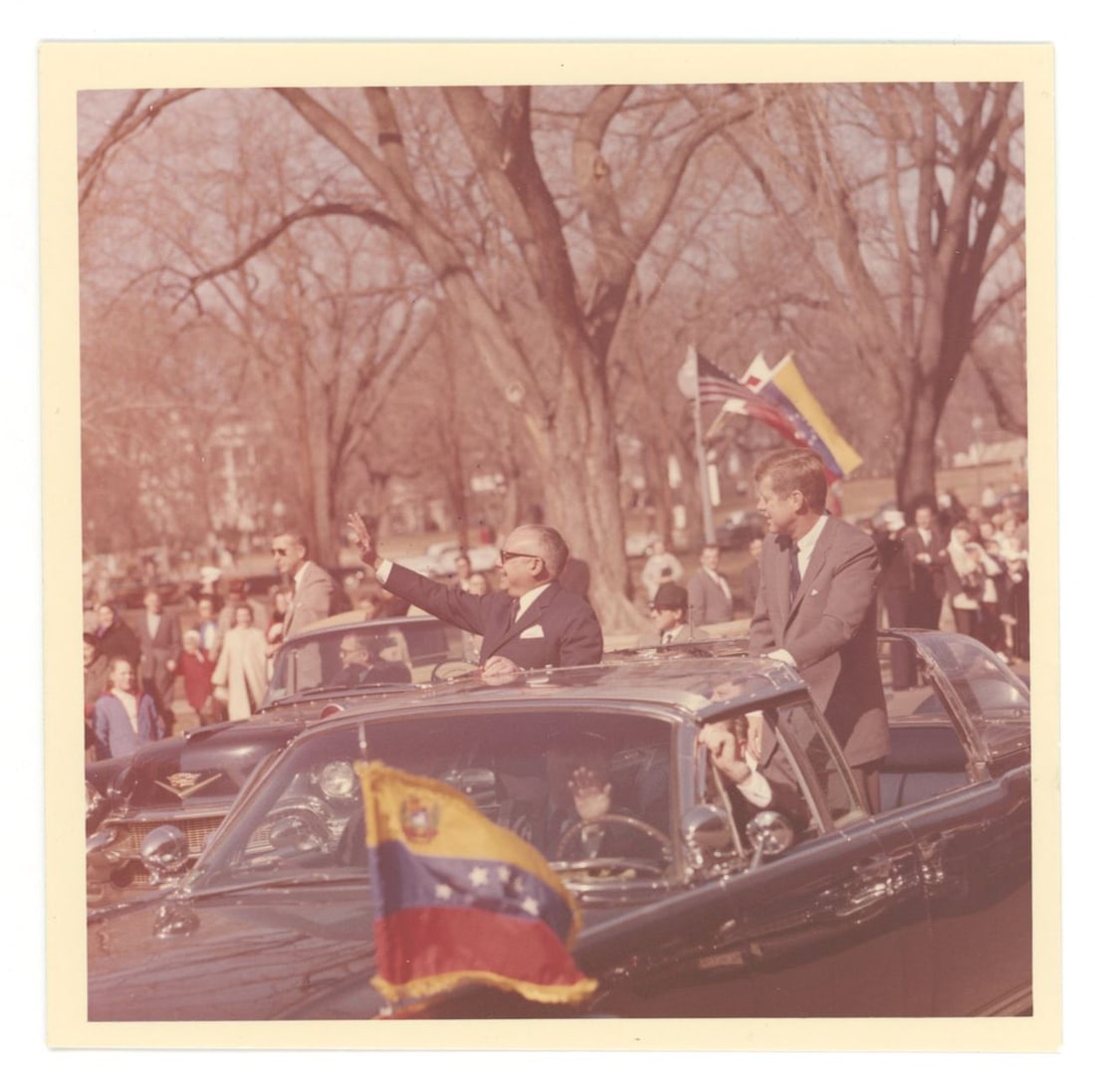 John F. Kennedy – Motorcade Appearance with Foreign Dignitary – Original 5 × 5 Ceci: Details: John F. Kennedy original 5 × 5 inch color photograph by White House photographer Cecil W. Stoughton, capturing President Kennedy riding in an open motorcade alongside a foreign