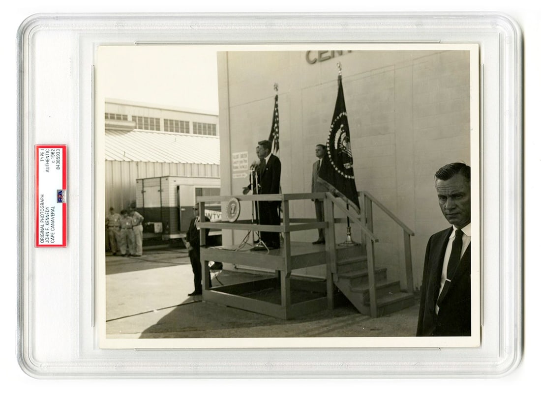 John F. Kennedy – Cape Canaveral Address – Type I Original 10 x 8" Photograph: Details: John F. Kennedy original Type I 10 x 8” press photograph depicting the President delivering remarks at Cape Canaveral, Florida, with American and Presidential flags displayed behind