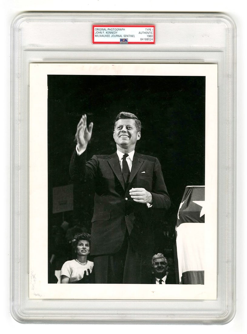 John F. Kennedy – Presidential Campaign Rally – PSA Type I Original 8 x 10" Photograph: Details: John F. Kennedy original 8 x 10” black-and-white press photograph, depicting Kennedy addressing a large crowd during a presidential campaign rally, captured mid-gesture at the podium.