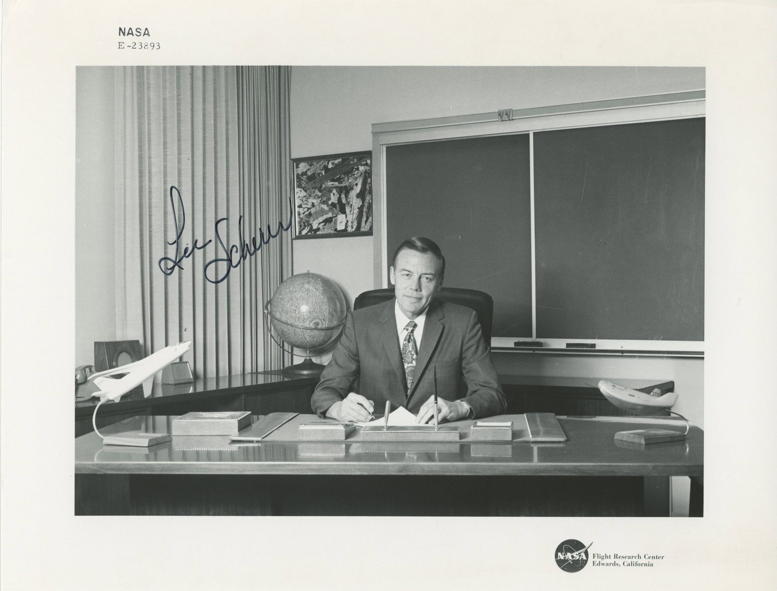 Lee R. Scherer – NASA Flight Research Center Director – Autographed Photograph – 1: Details: Lee R. Scherer autographed 10 × 8-inch black-and-white NASA photograph depicting Scherer seated at his desk in an administrative office setting at the NASA Flight Research Center,