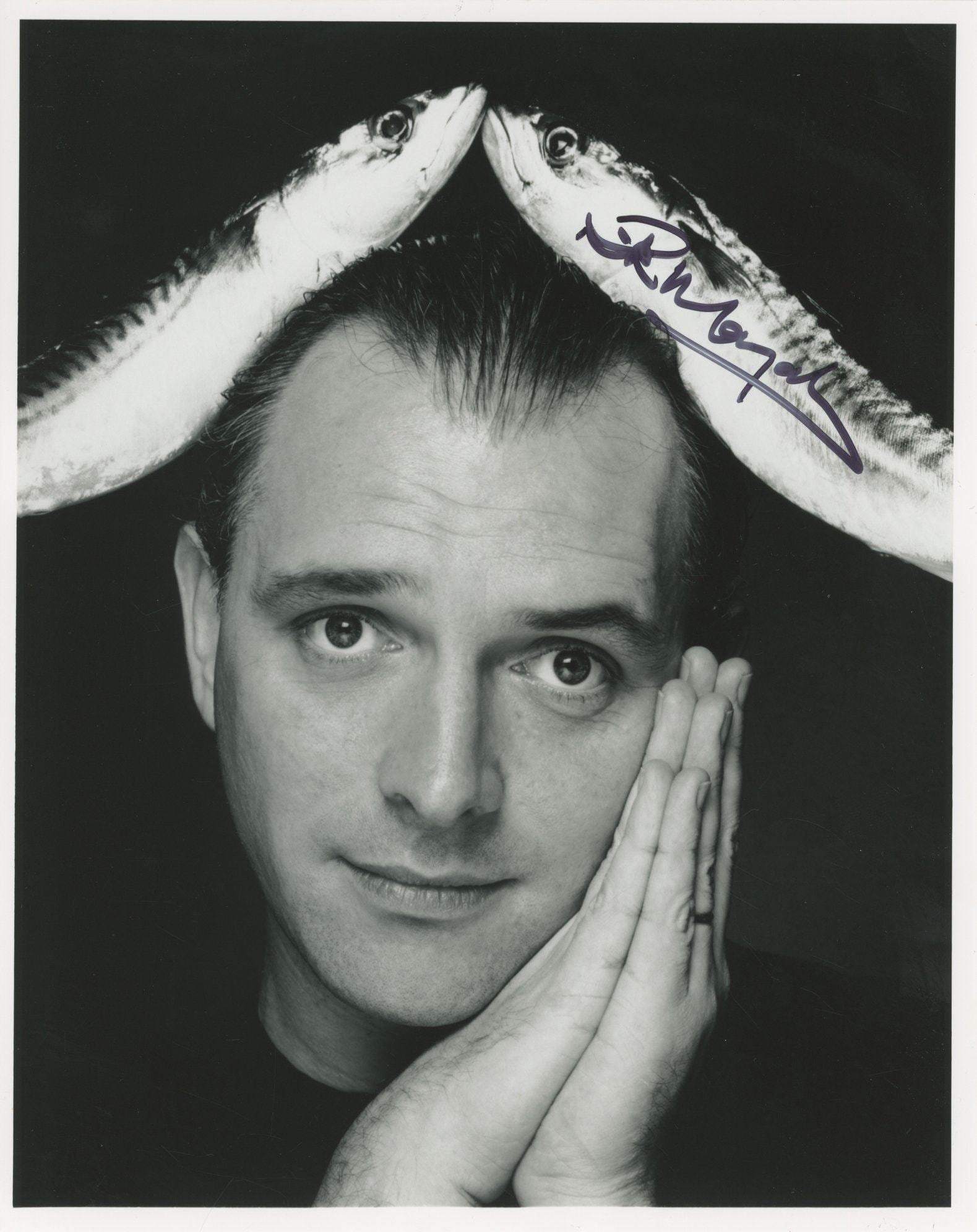 Rik Mayall – British Comedian & Actor – Autographed 8 x 10 Photo – Portrait: Details: Rik Mayall autographed 8 x 10” glossy photograph depicting a stylized portrait of the comedian posed with hands against his face and fish positioned above his head. Boldly signed in dar