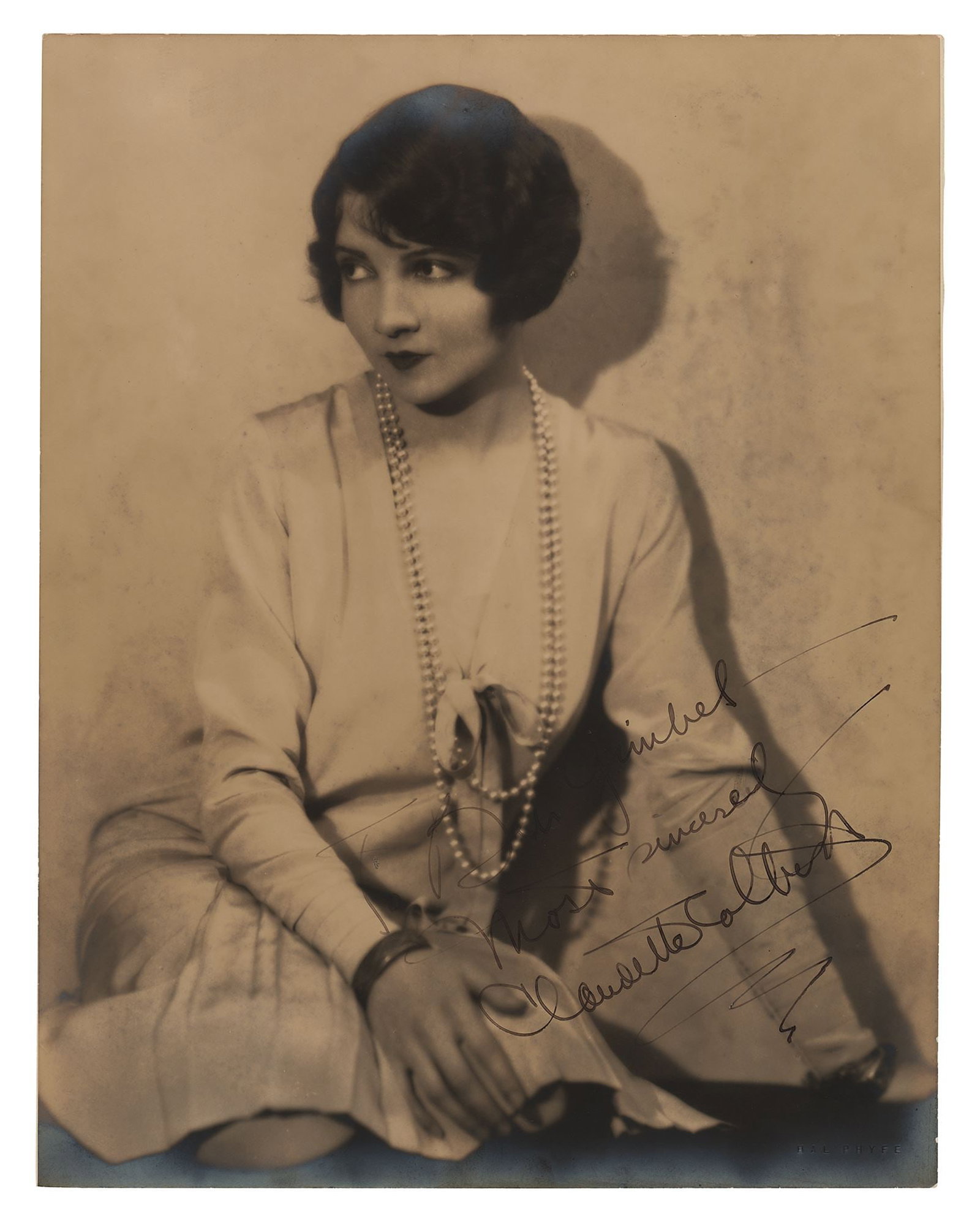 Claudette Colbert – Academy Award Winner – Autographed 11 x 14 Photograph – Hal Ph: Details: Claudette Colbert autographed 11 x 14” double-weight vintage photograph depicting a softly lit studio portrait of the actress seated in elegant attire, adorned with a long strand of pea