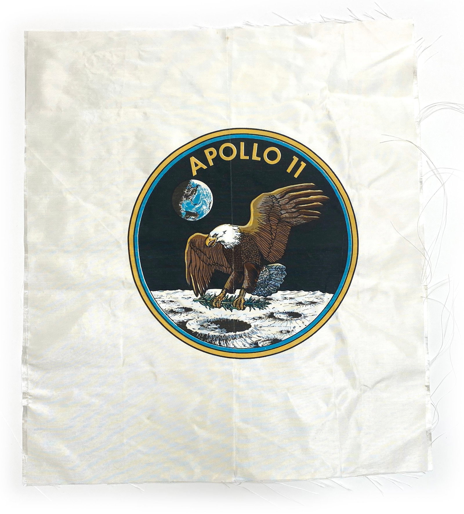 Apollo 11 Mission Insignia Beta Cloth – Oversized NASA Display Textile: Details: Oversized Apollo 11 Beta cloth display textile measuring approximately 17.5 x 20” featuring the iconic Apollo 11 mission insignia prominently printed at center. The design depicts the