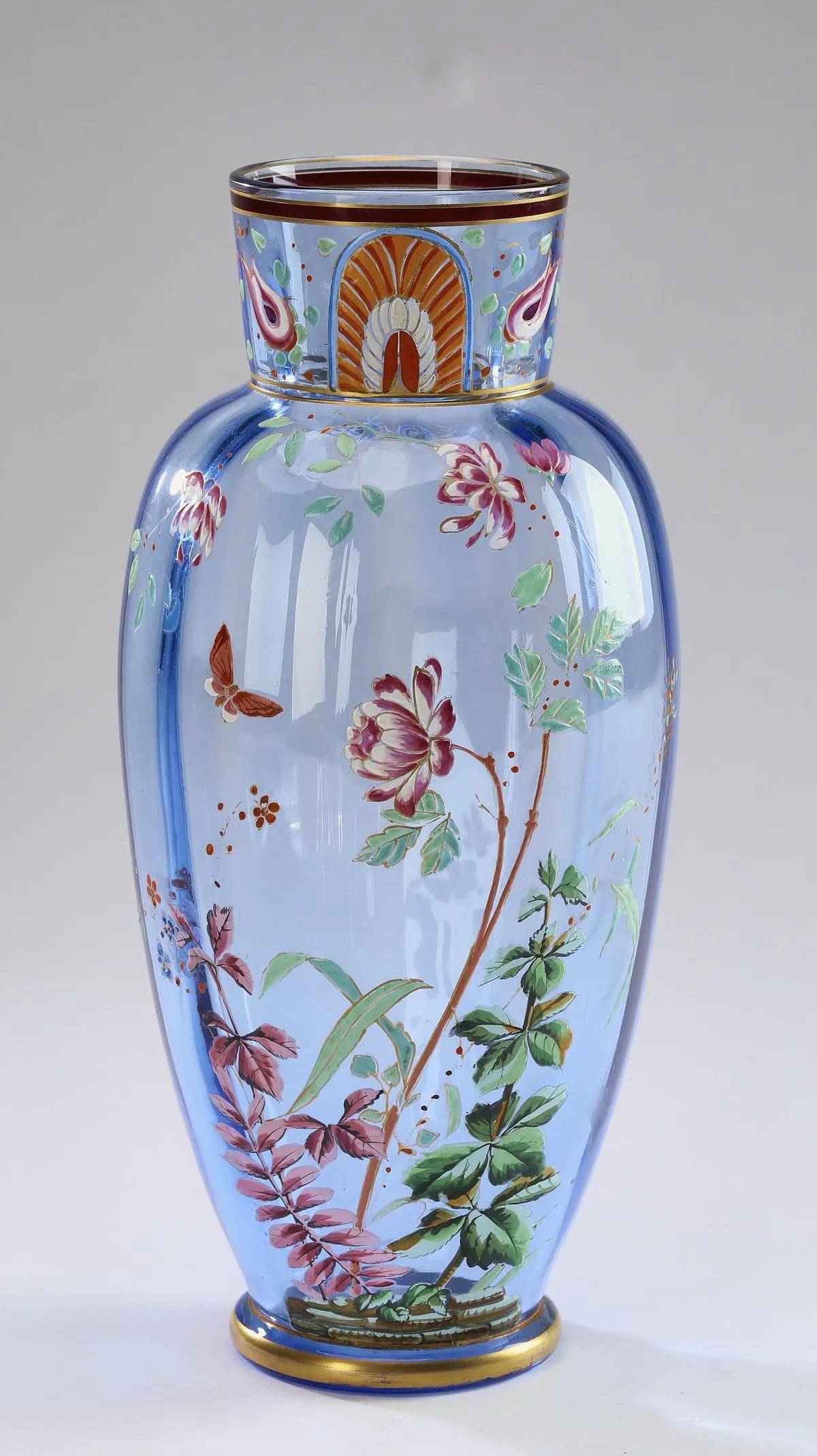 Continental enameled blue glass vase: Continental enameled blue glass vase, of baluster form, having a short cylinder neck above an ovoid optic body decorated with a floral spray of chrysanthemums and a butterfly, 11.25"h x 4.5"dia.