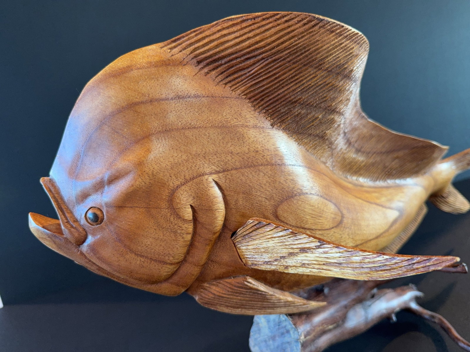 Hand-Carved Wooden Mahi Fish Sculpture: Hand-carved wooden Mahi fish sculpture, featuring detailed fin and body work, and presented on a natural wood base. This decorative piece displays skillful artistry and smooth finish throughout.
