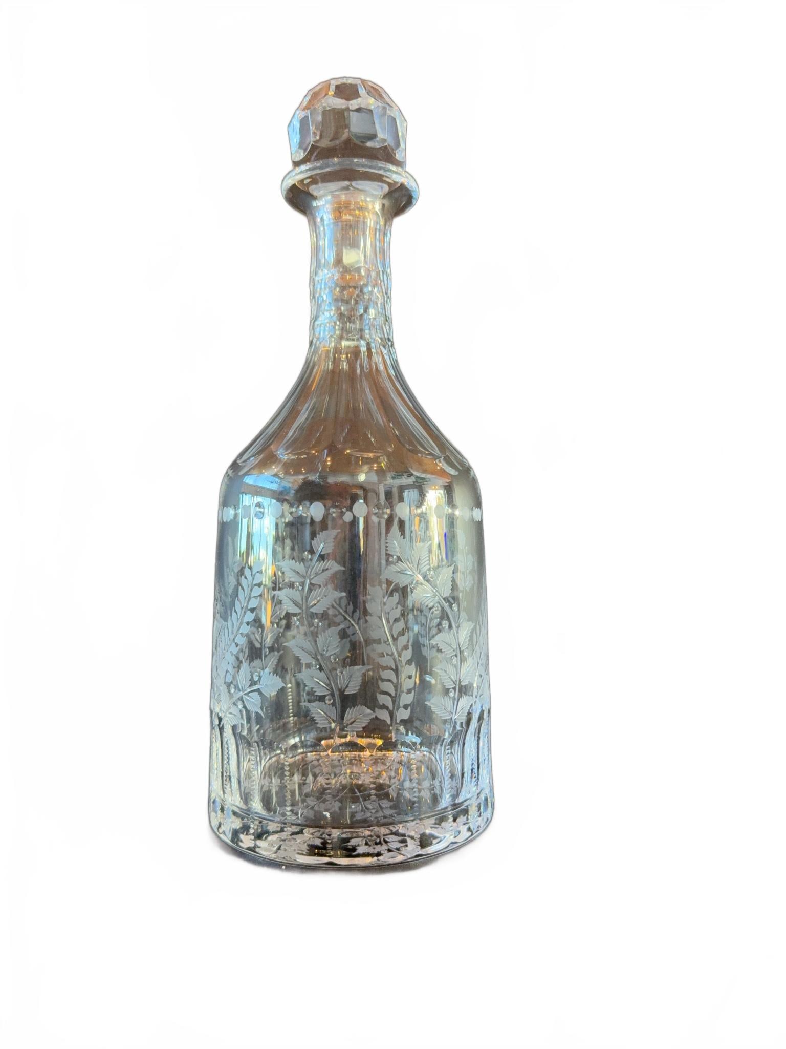 Cut Crystal Decanter with Stopper: Clear cut crystal decanter featuring an etched fern motif and faceted stopper. The body displays detailed botanical patterns with circular banding along the top. Complete with matching stopper.