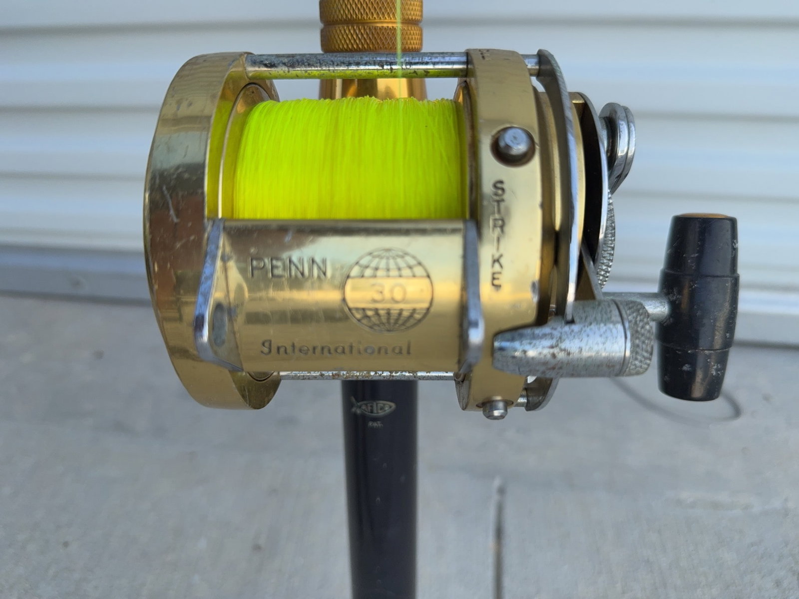 Penn International 30 Big Game Rod and Reel: Penn International 30 big game saltwater fishing rod and reel combo with gold finish and bright yellow line. The reel is marked "Penn International 30" and "Strike" with a reset lever. Shows normal