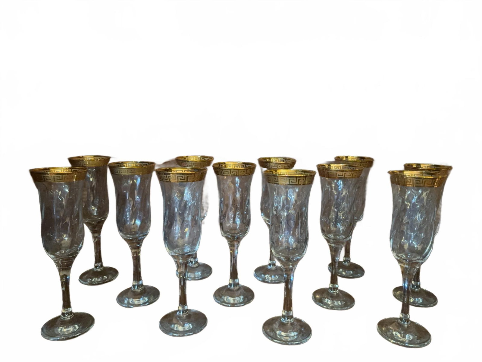 12 Crystal Champagne Flutes with Gold Greek Key Rim: 12 clear crystal champagne flutes featuring a gold Greek key patterned rim. These glasses have a classic shape and elegant detailing, suitable for formal occasions or display. All glassware is free