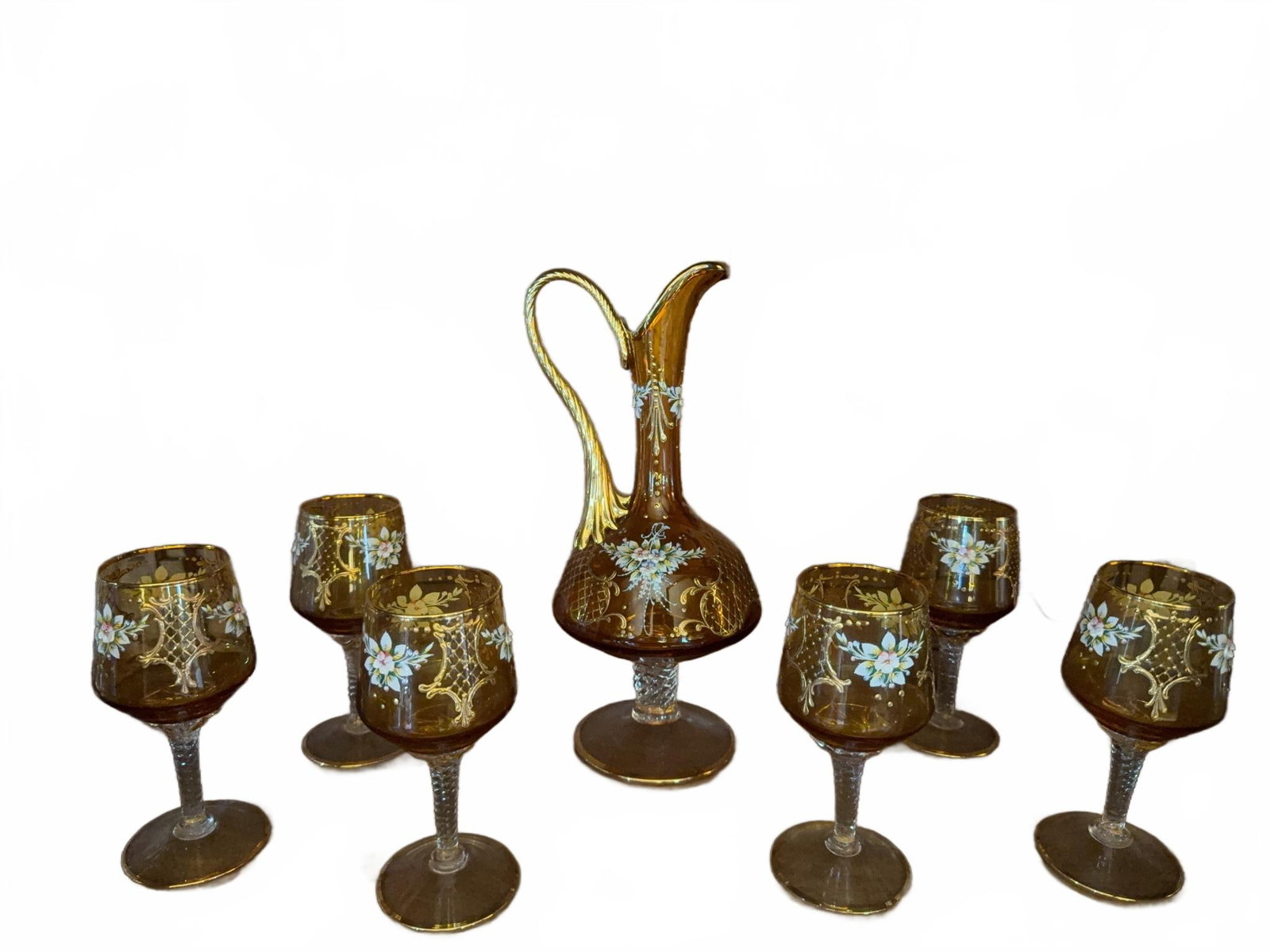 Amber Glass Decanter With 6 Stemmed Glasses: Amber glass decanter and six matching stemmed glasses, each decorated with hand-painted floral and gold gilt designs. The decanter features a spiral handle and clear stem, echoed by the twisted clear 