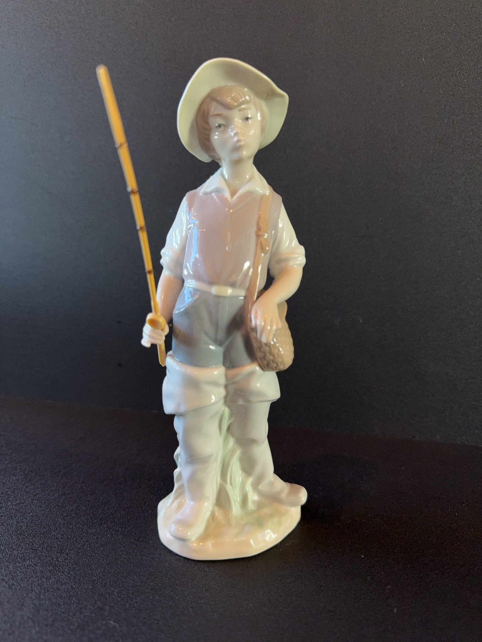 Lladro Fisher Boy Gone Fishing Porcelain Figurine: Lladro "Gone Fishing" orcelain figurine depicting a young boy holding a fishing rod and basket. Features hand-painted details and glossy finish. Marked "Lladro Handmade in Spain" on the base. Overall 