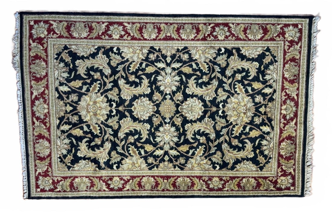 6' X 4' Oriental Rug with Floral Motif: Oriental Rug area rug featuring a central floral pattern with gold and beige motifs set against a black field. The rug has a detailed red and gold border and white fringes on the ends. Traditional des